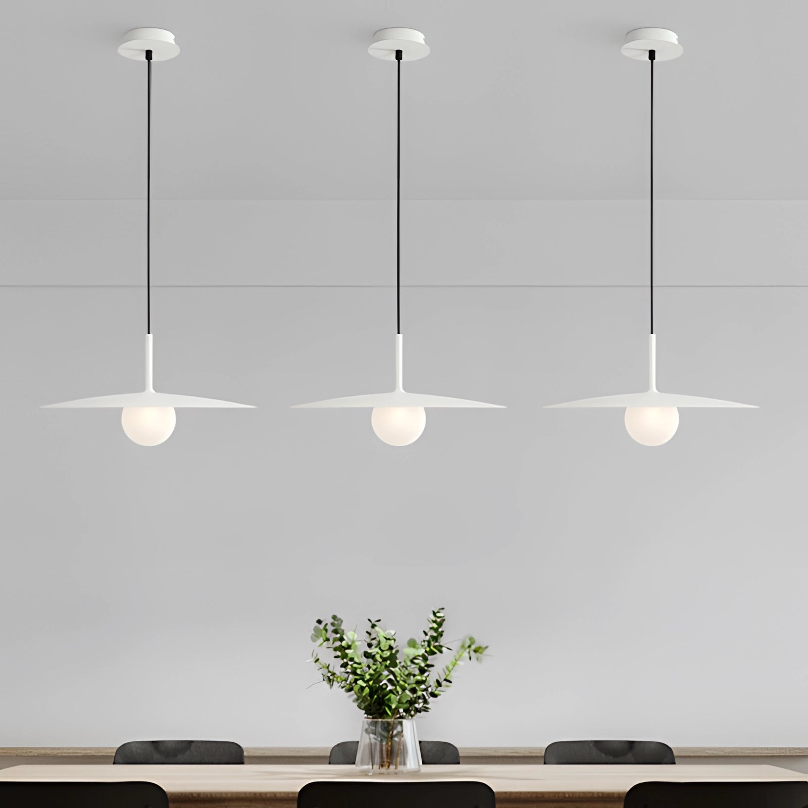 Minimalist black pendant lamp with Scandinavian design, featuring a white variant, hanging above a table with houseplants and vases.
