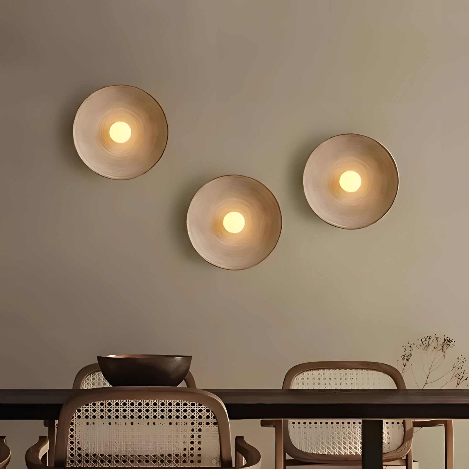 Minimalist bronze circular wall art piece displayed on a wall in a well-designed interior setting with wooden elements and subtle lighting.