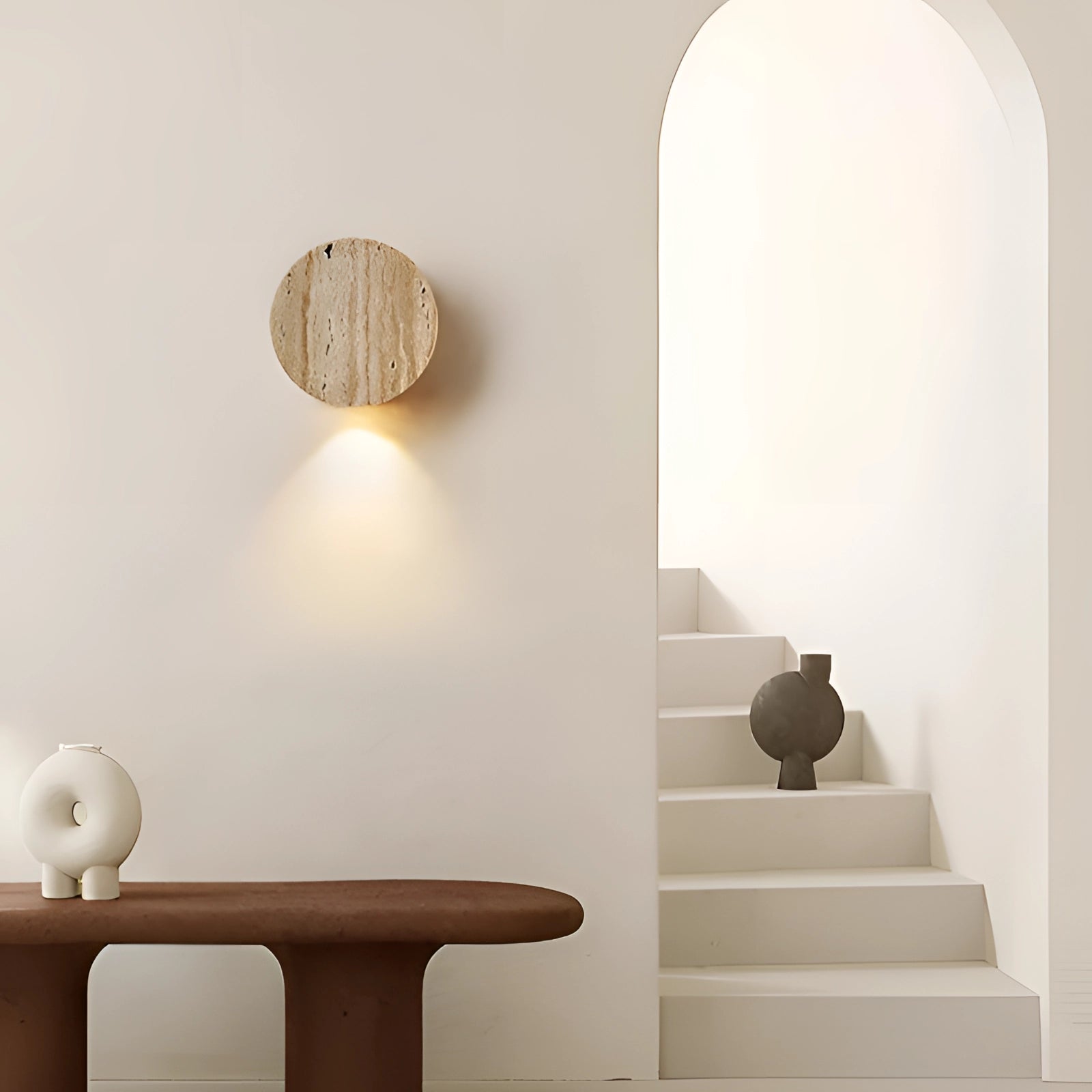 A minimalist circular wooden wall sconce mounted on a white wall, emitting soft light, embodying Scandinavian design aesthetics for contemporary interior spaces.