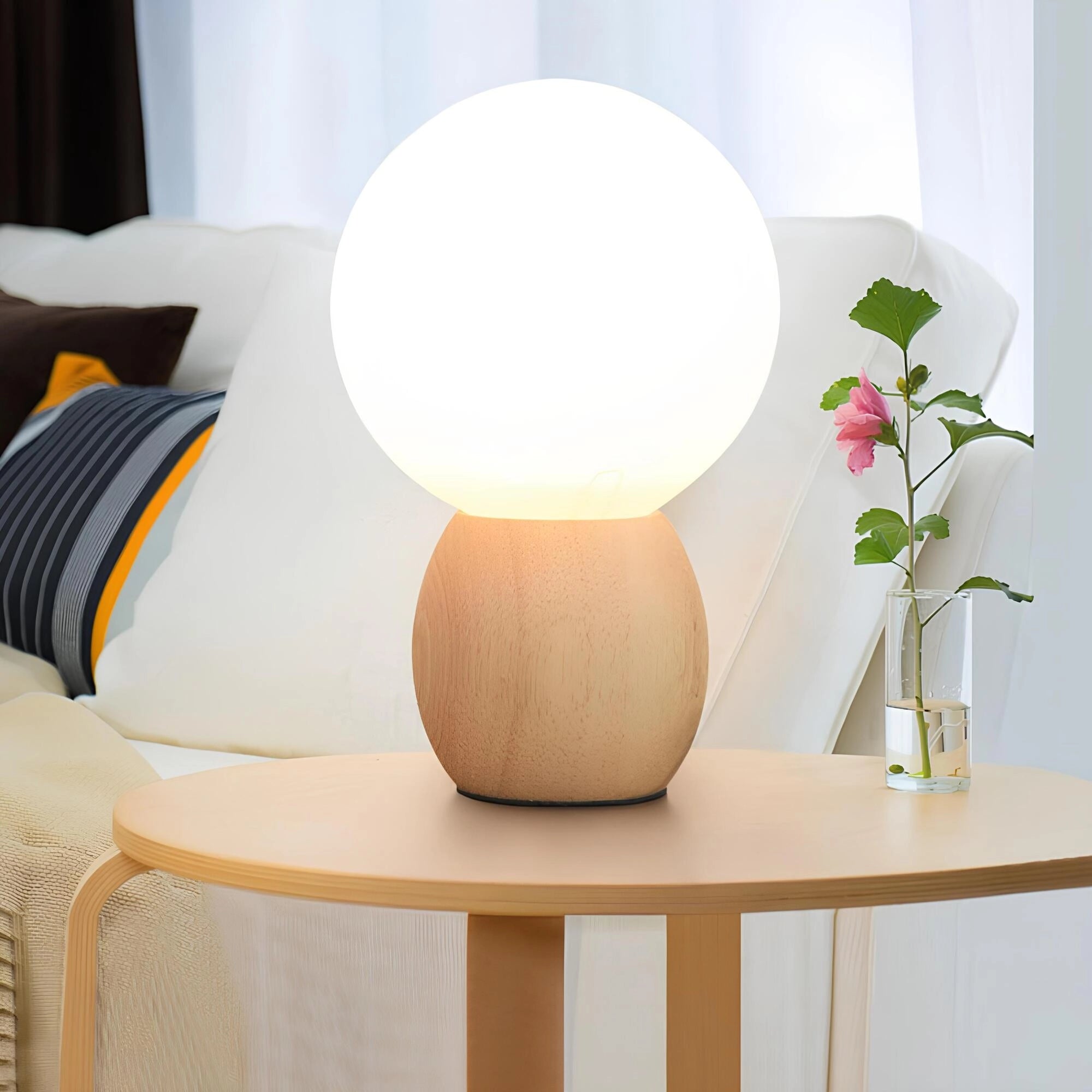 Minimalist glowing bedside lamp with a wooden base, emitting soft ambient light. The lamp is placed on a table alongside a plant in a vase, enhancing the interior design with its warm and comforting glow.