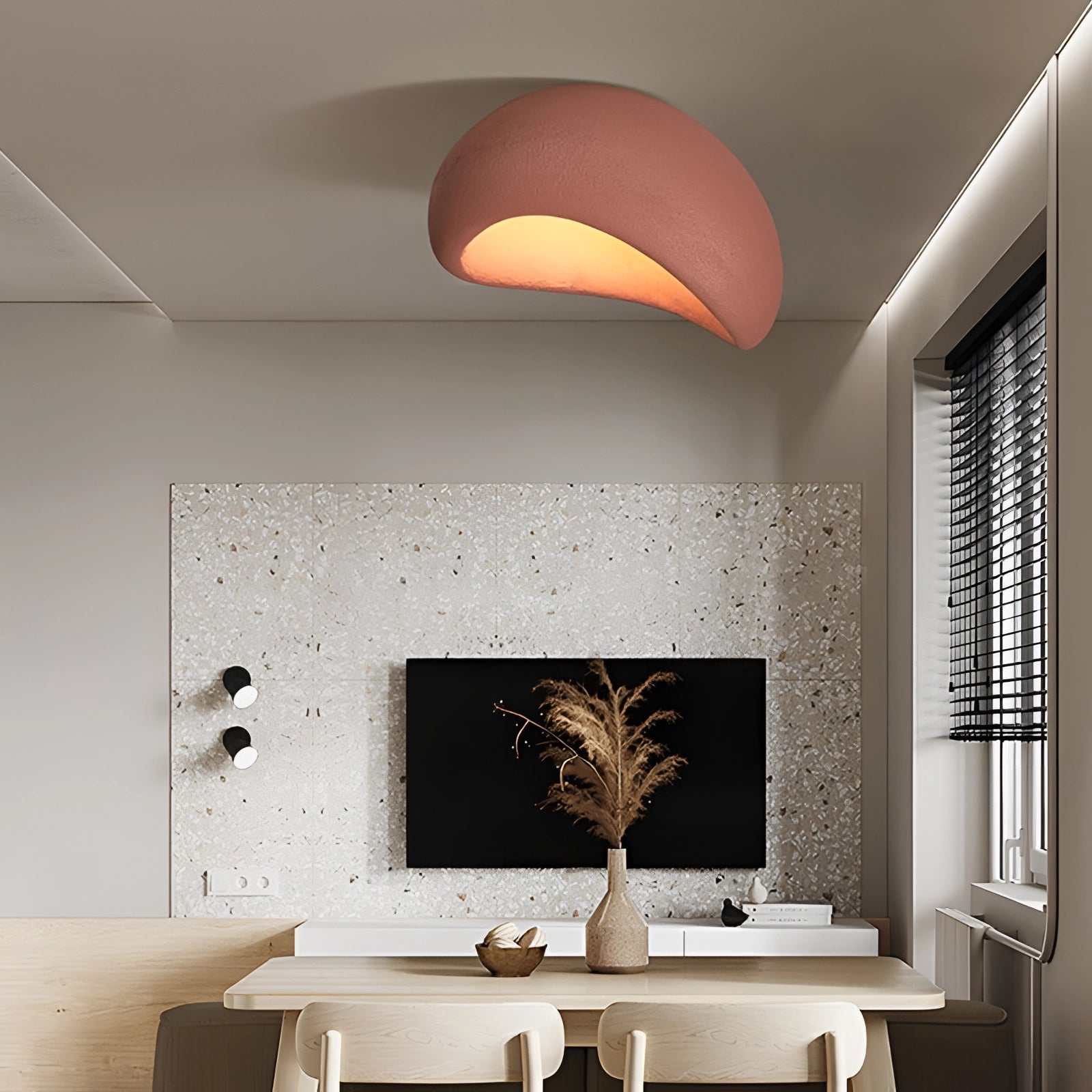 Minimalist half-moon wall sconce in red with a bevel connection, illuminating a modern living room with ambient lighting; surrounded by furniture, including a wooden table and potted plant, enhancing the interior design.