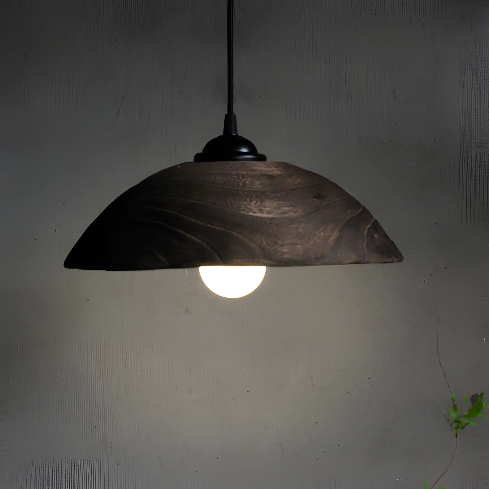 Minimalist industrial LED pendant light with a modern textured design, featuring a circular shade and hanging from the ceiling. The lamp's sleek and contemporary style complements any modern interior setting.