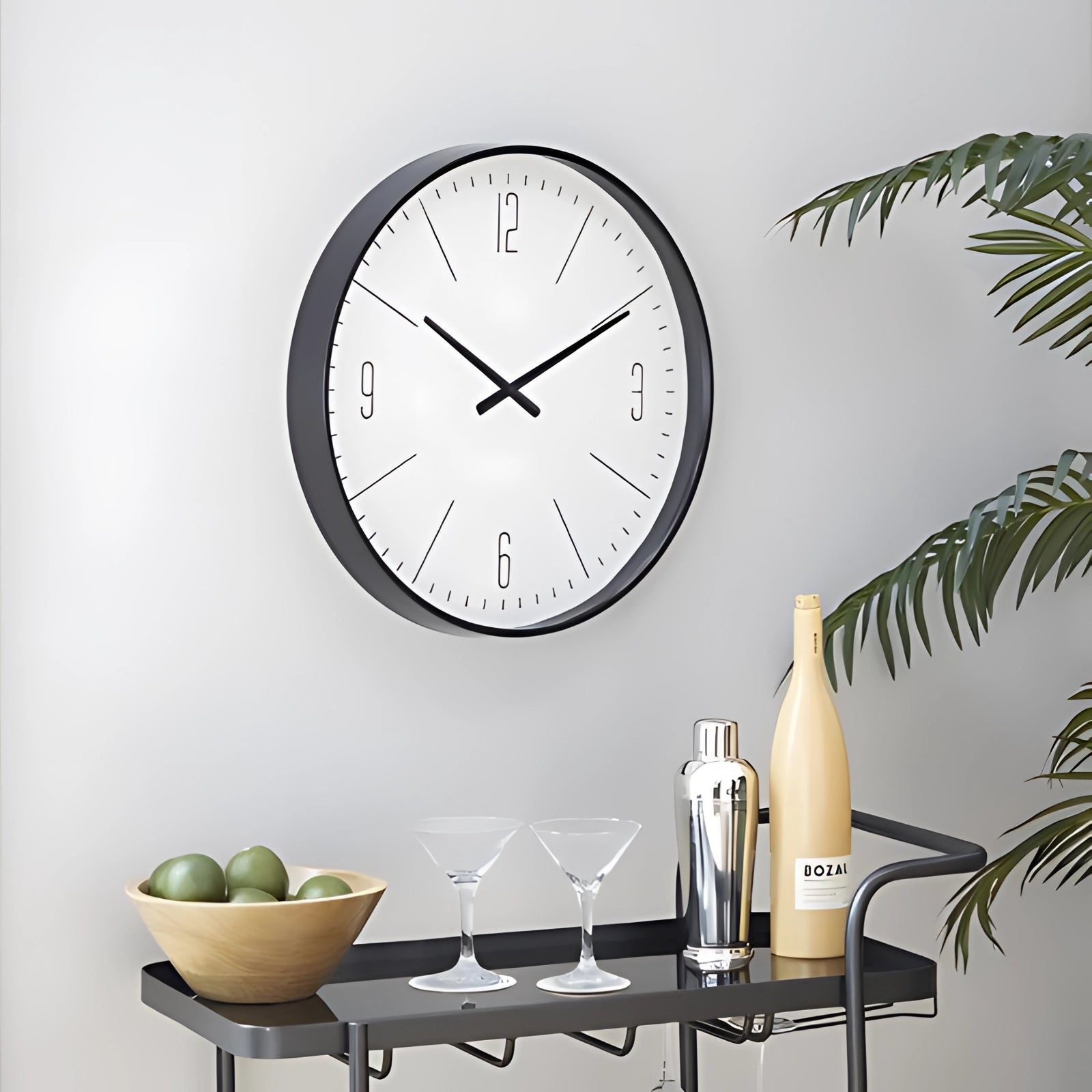 Minimalist large white wall clock with a modern black frame hanging on a wall, accompanied by a wooden table and decorative plants, creating a contemporary interior design setting.