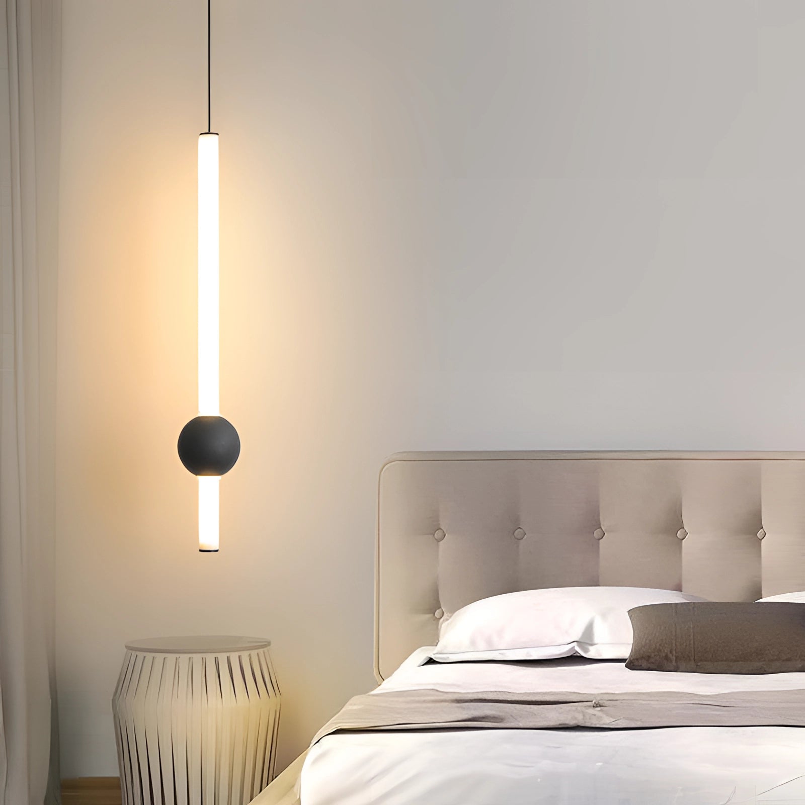 Minimalist LED pendant light featuring a black and white cylindrical globe design, emitting warm white light, suspended in a contemporary interior setting.