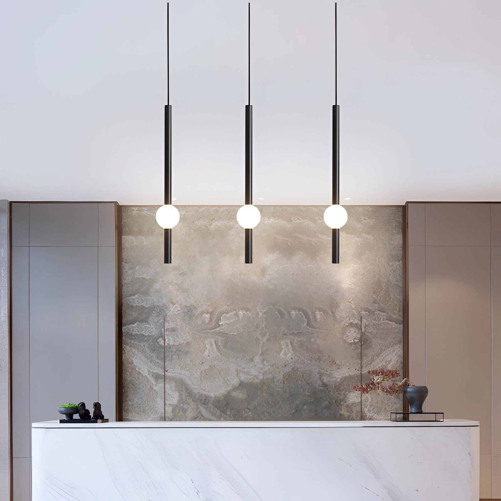 Minimalist LED pendant light featuring a black and white cylindrical globe, hanging in a modern interior space with wooden accents, grey tones, and a nearby flowerpot.
