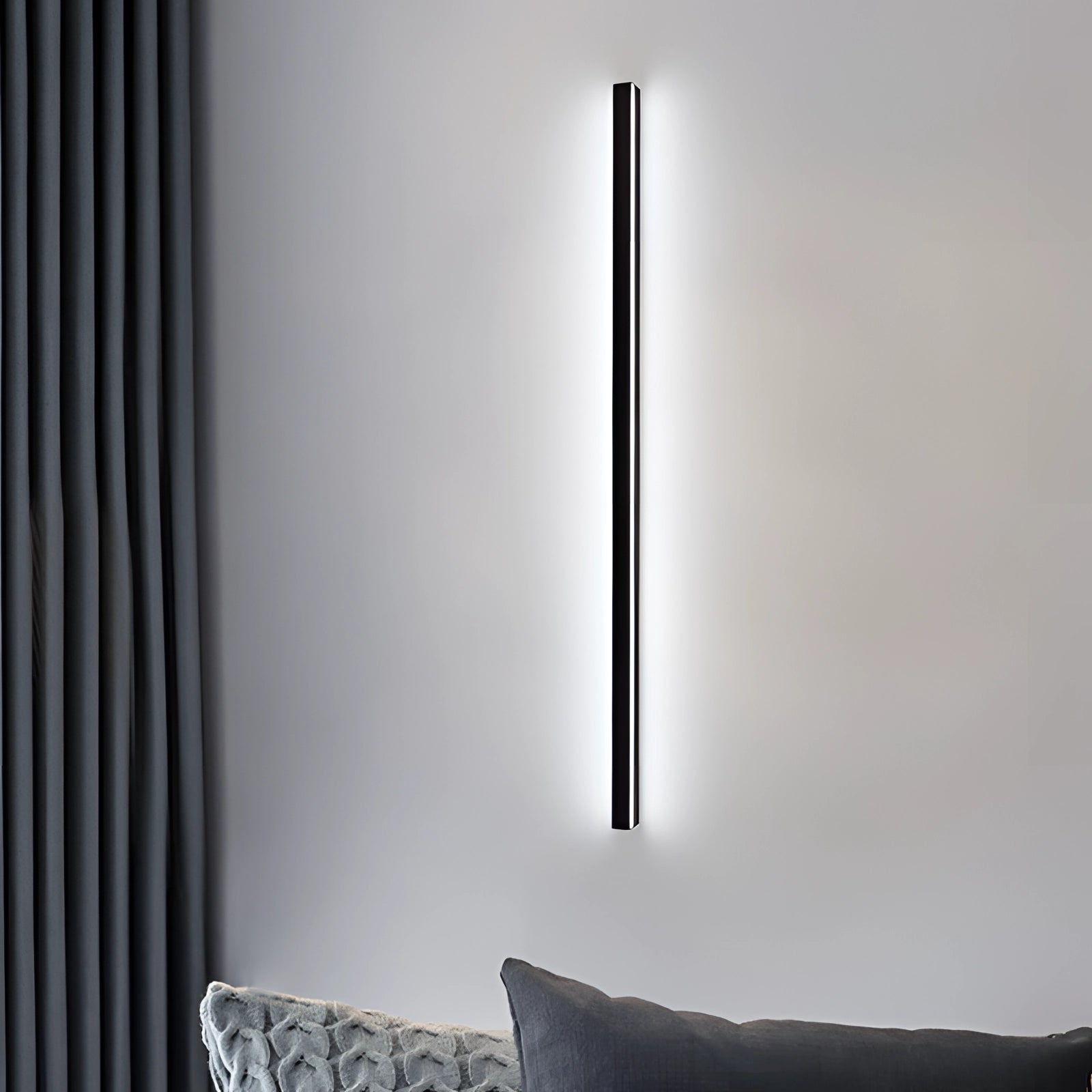 Minimalist LED wall sconce mounted on a grey wall above a modern grey couch in a stylish living room with wooden flooring.