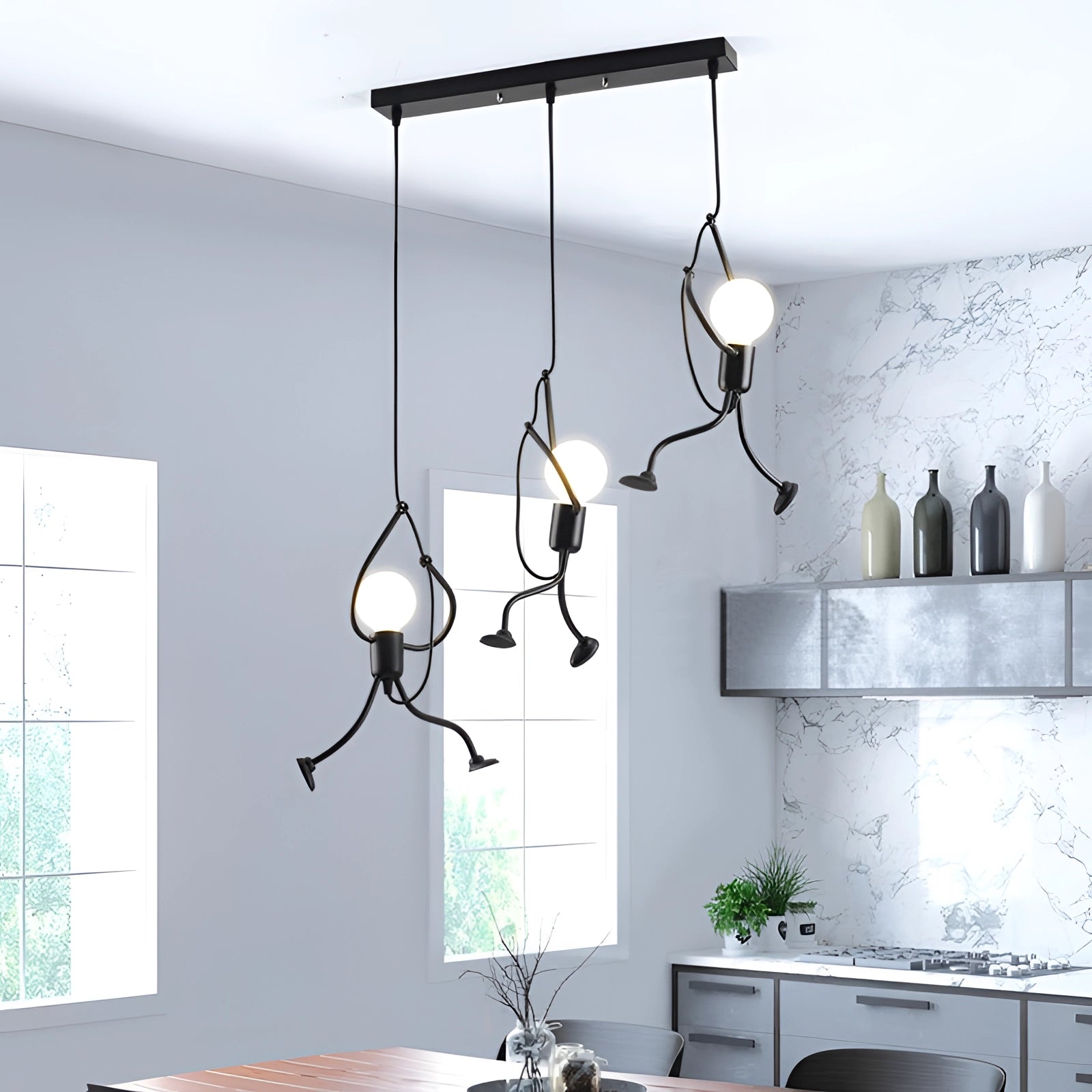 A minimalist modern pendant light with an adjustable metal ceiling fixture hangs in a stylish interior setting featuring a white table, green plant, and large window. The room showcases contemporary design elements with wooden and grey accents.