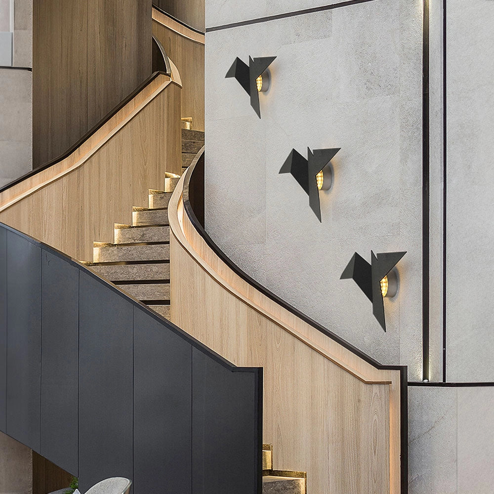 Minimalist Origami Bird LED Wall Lamp with geometric modern design, featuring a wooden and metal composite fixture mounted on a wall near a staircase with a symmetrical rectangular facade.