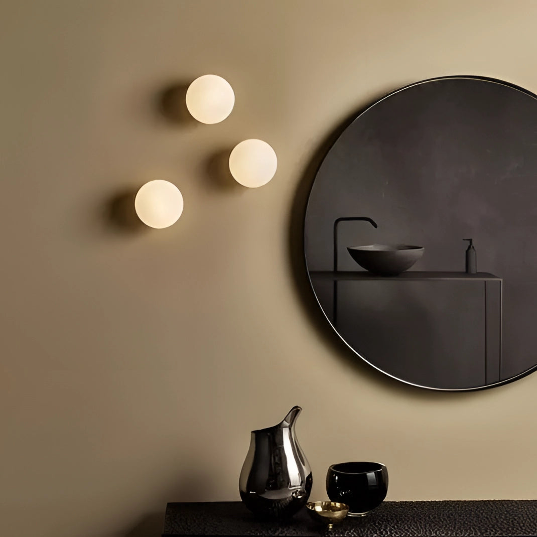 Minimalist round LED wall light with a wooden finish, mounted on a bathroom wall, emitting a soft, warm glow.