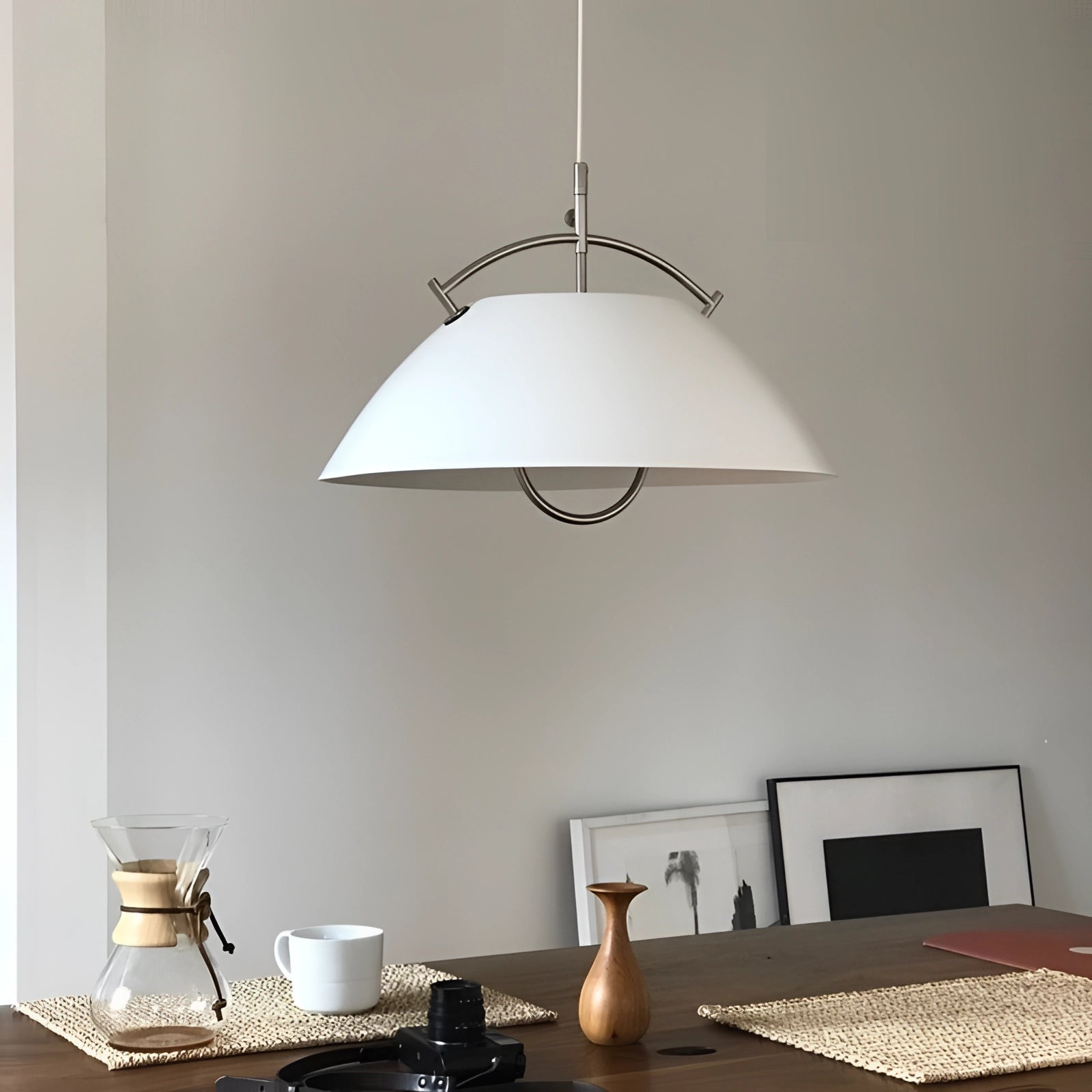 Minimalist Scandinavian white pendant light hanging above a wooden table in a modern interior setting, showcasing its adjustable lamp shade and sleek design.