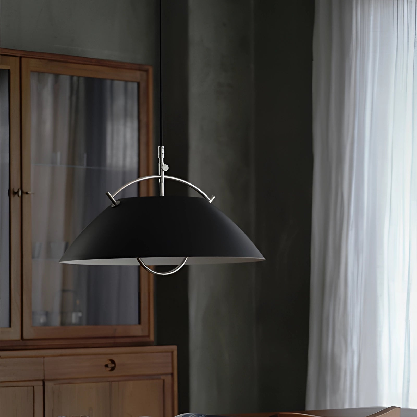 Minimalist Scandinavian white pendant light hanging above a modern kitchen with wooden cabinetry, grey countertop, and neutral interior design elements.