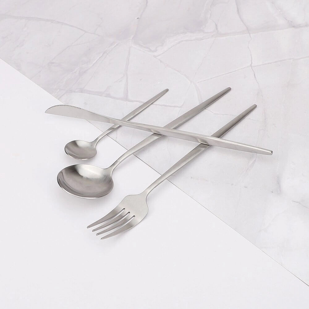 Minimalist stainless steel cutlery set, featuring elegant flatware pieces made of sleek metal, displayed on a table setting.