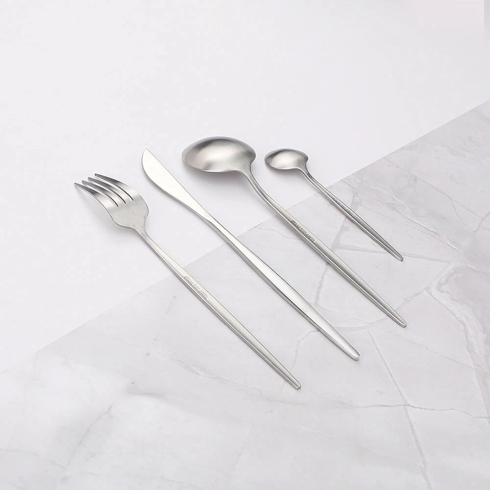Minimalist stainless steel cutlery set including a fork, knife, and spoon displayed elegantly on a table.