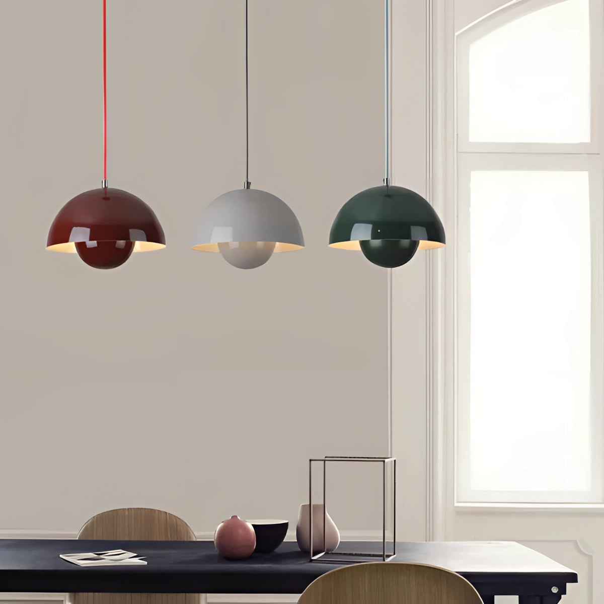 Minimalist white dome pendant light with a Scandinavian design hanging in a modern dining and kitchen area, featuring wooden elements and a large window, with additional chairs and clean interior lines.