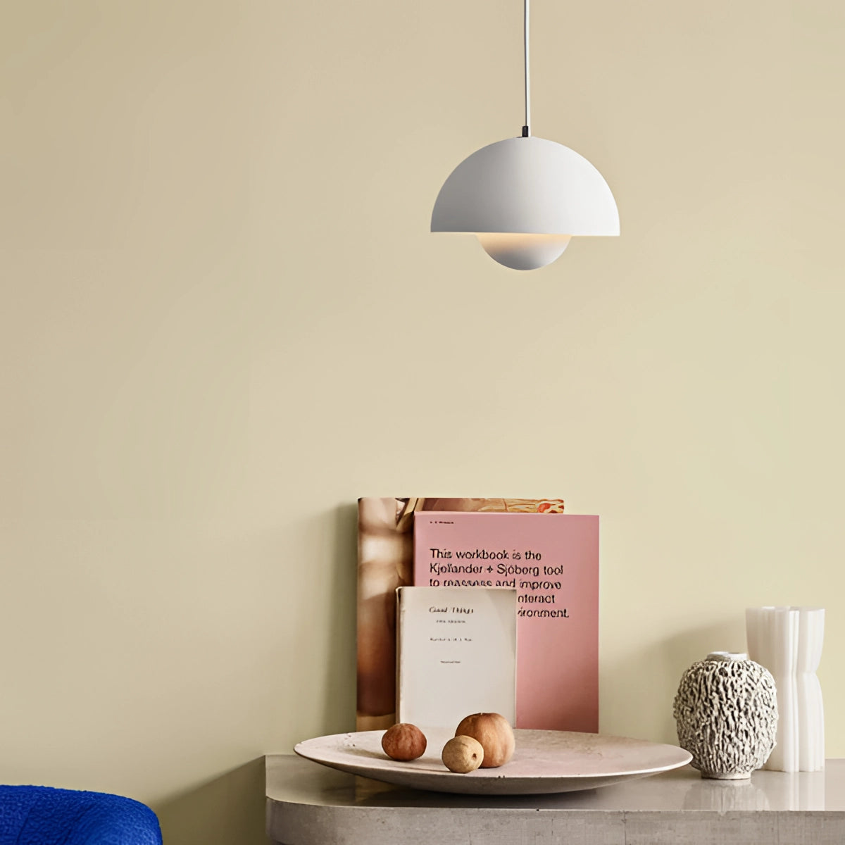 Minimalist white dome pendant light hanging above a dining table set with tableware and linens, showcasing a Scandinavian interior design style.