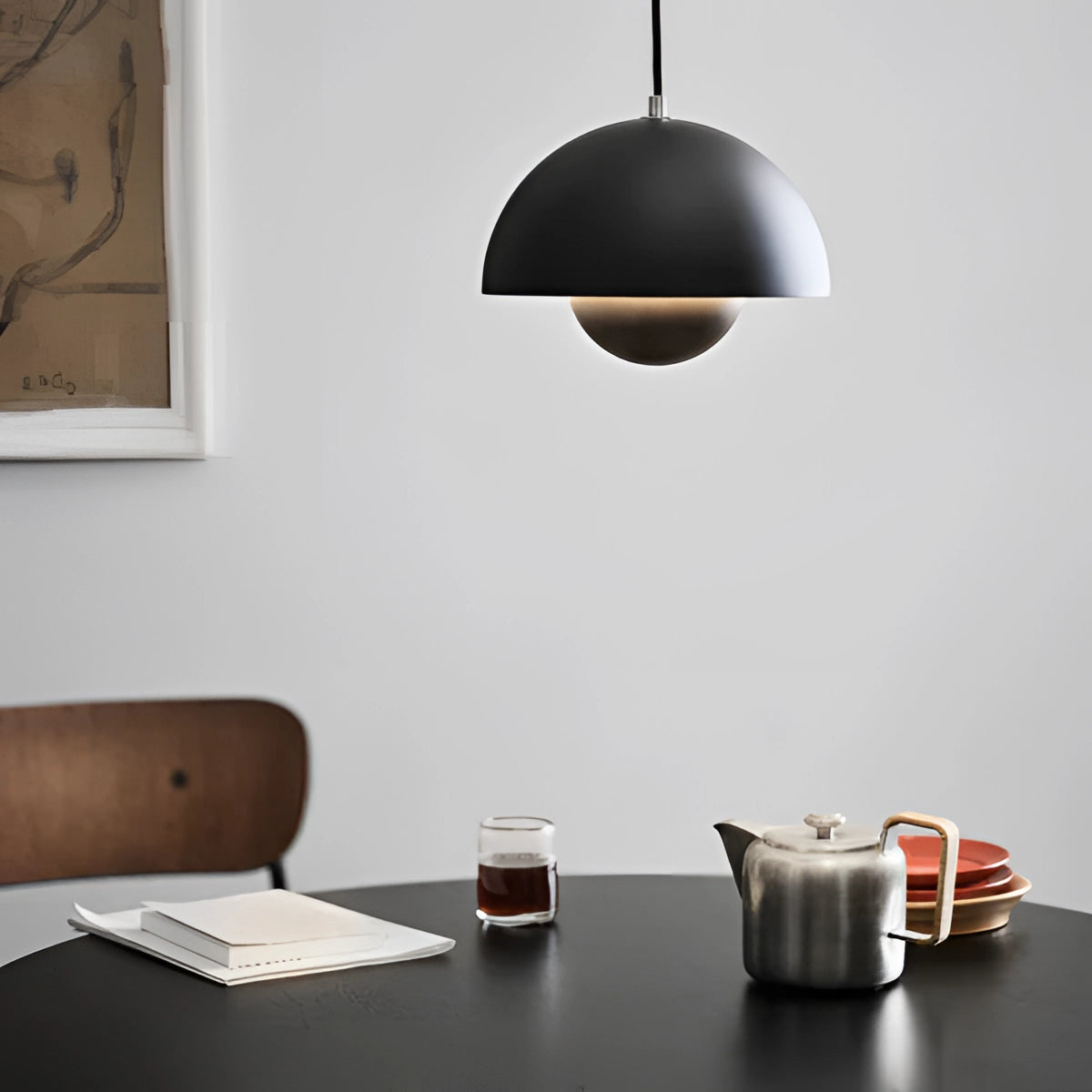 Minimalist white dome pendant light hanging above a wooden dining table set with tableware and cups, designed in a Scandinavian style for kitchen or dining areas.