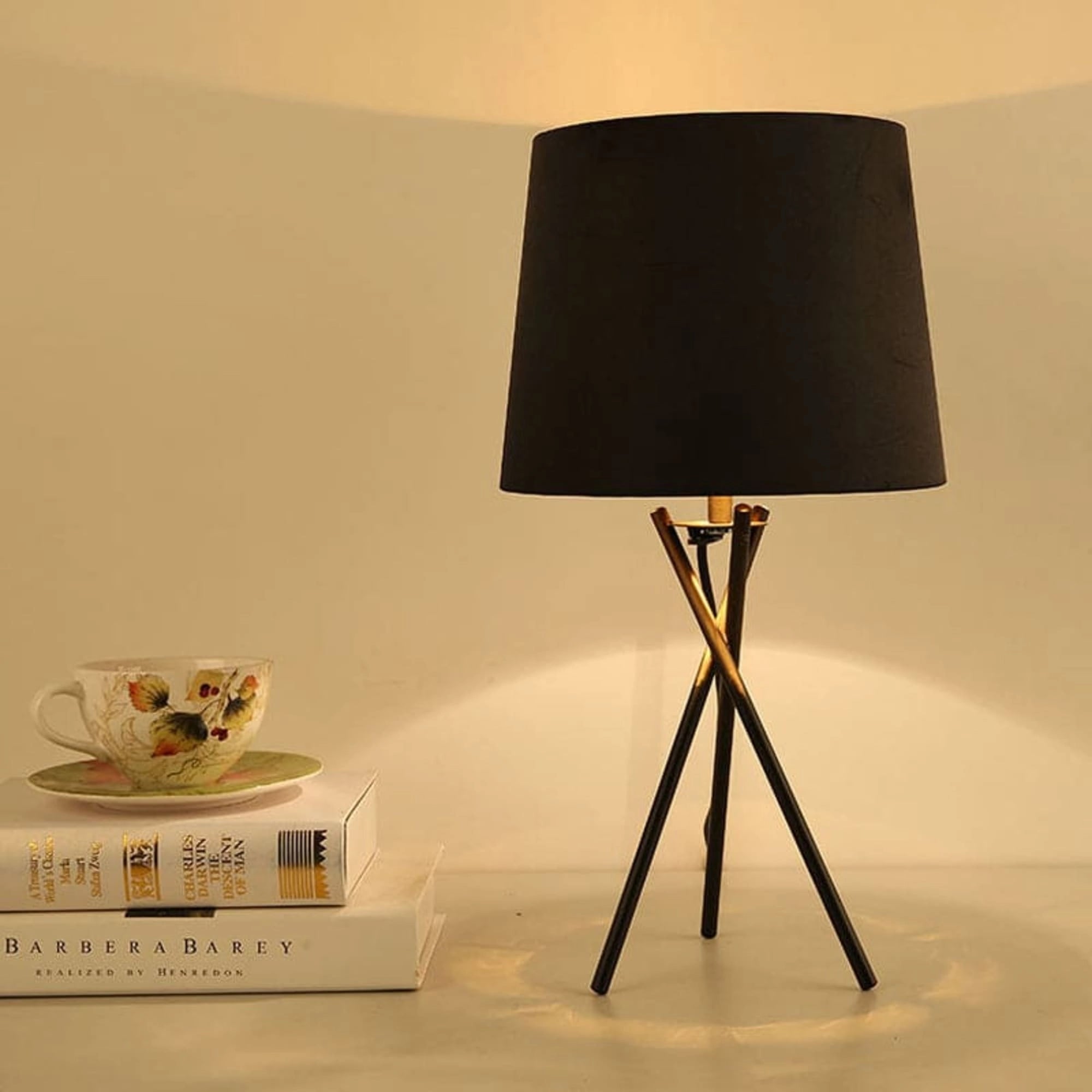 Minimalist white table lamp with a modern tripod base and a fabric shade, displayed on a wooden table surface.