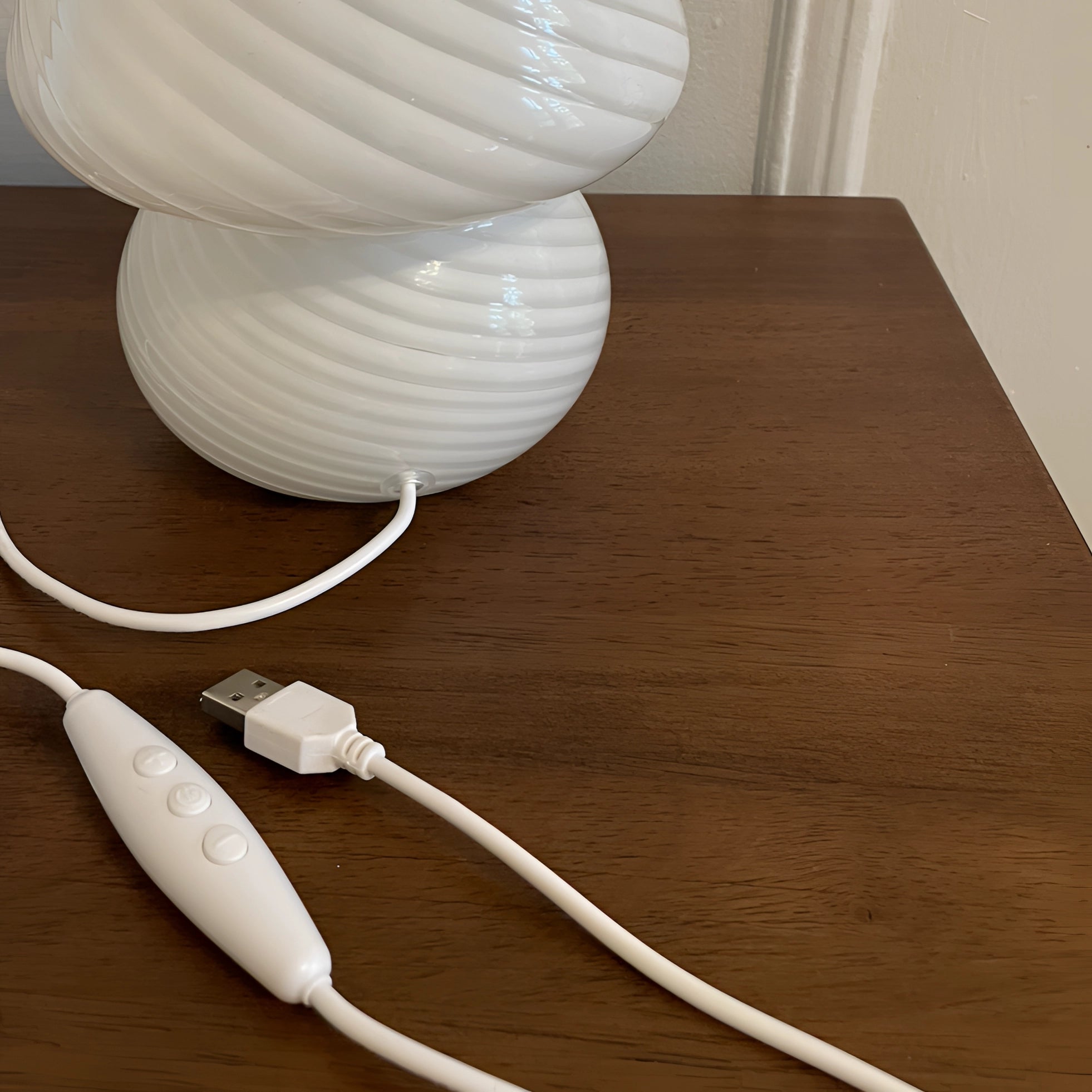 Modern 3D printed white swirl LED table lamp with an elegant design, featuring a wooden base and energy-efficient lighting.
