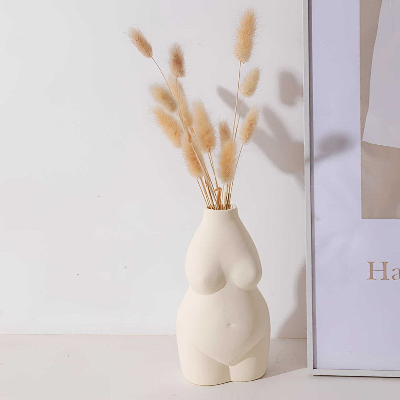 Modern abstract female form vase with an art deco body-shaped design, showcasing smooth curves and artistic detailing, made from natural materials and styled as a flowerpot, displayed with twigs for a creative, contemporary look.