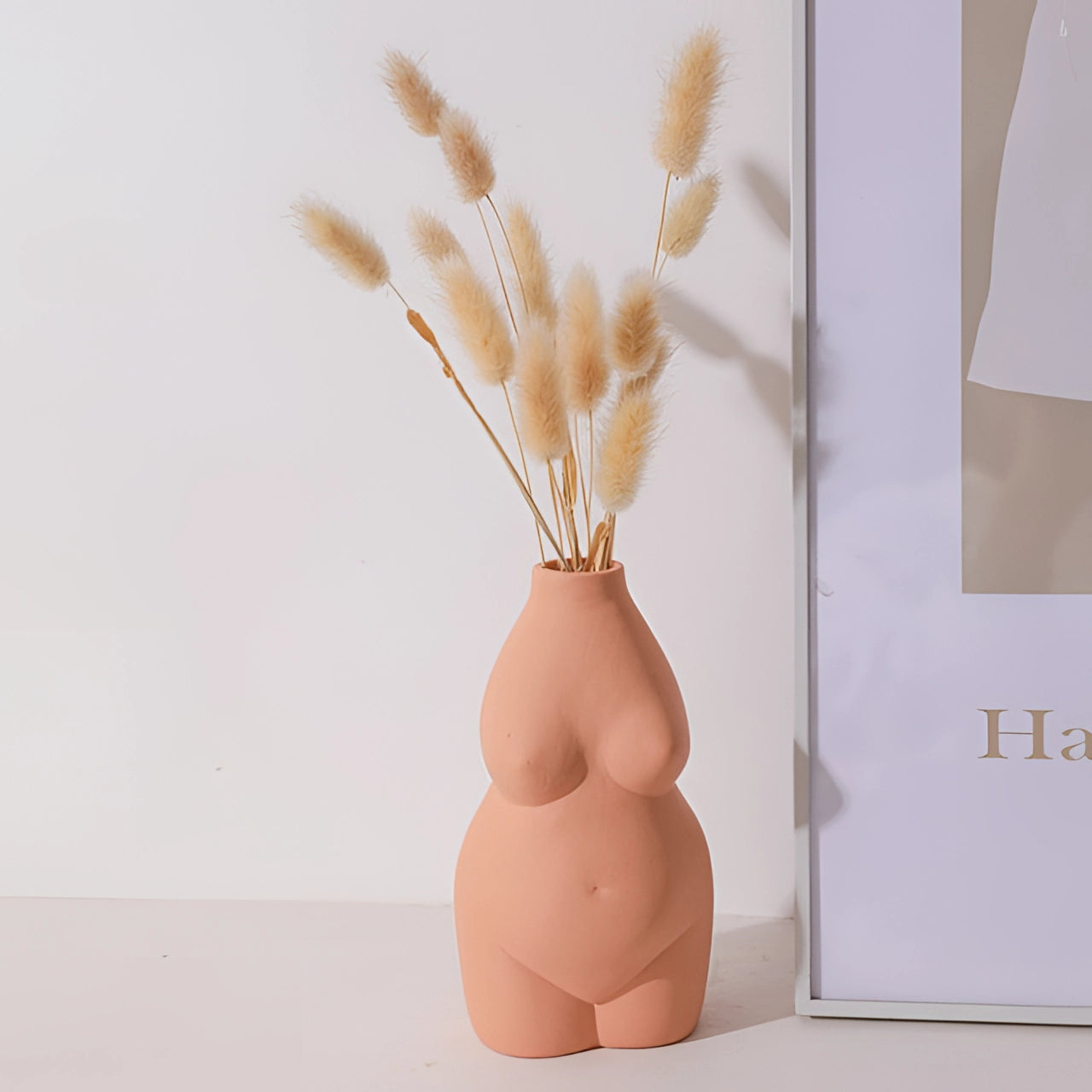 Modern abstract vase in an art deco body shape, colored in a vibrant orange hue, made from natural materials and featuring artistic details reminiscent of twigs and wood, displayed against a beige background.