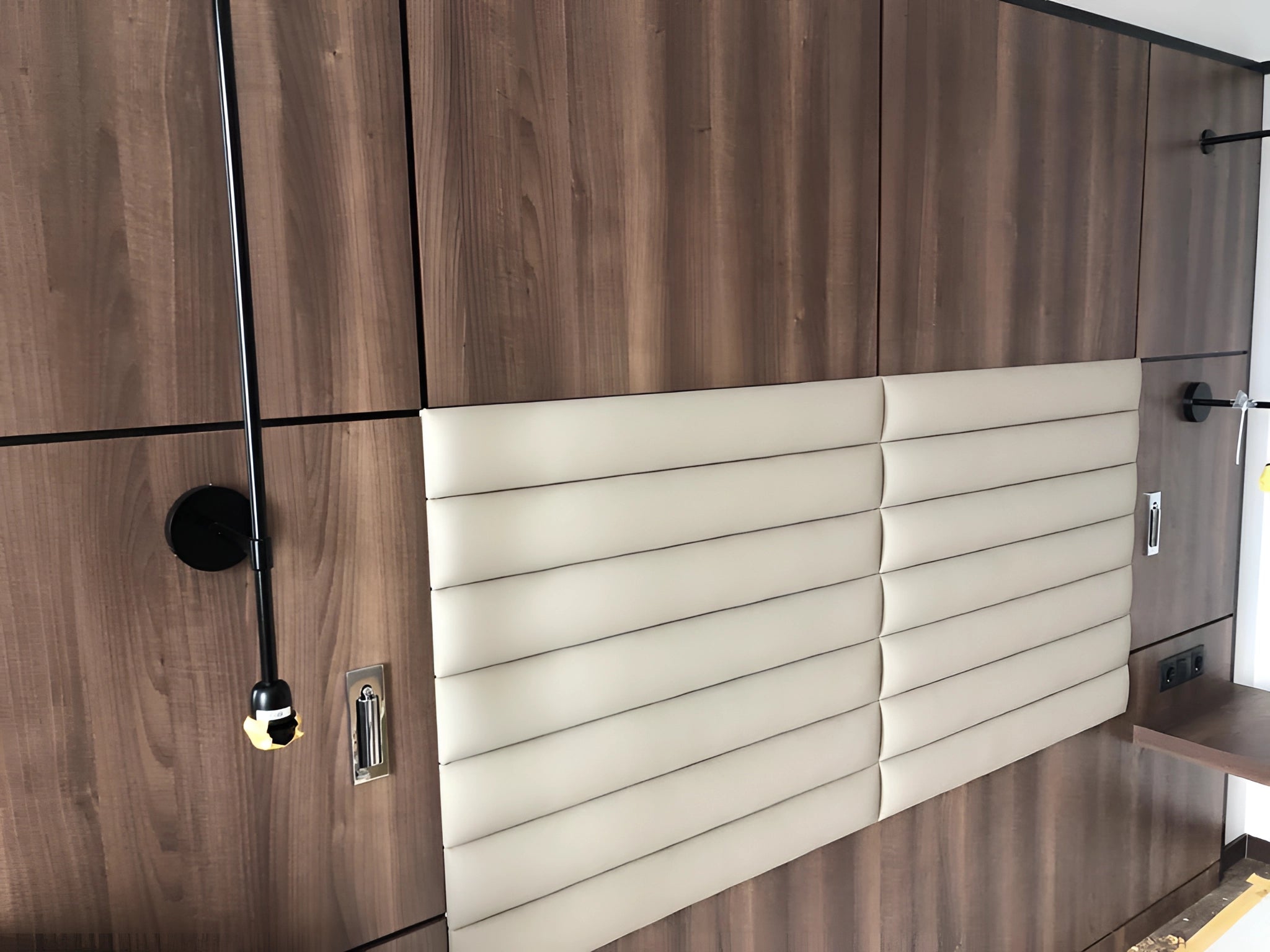 Modern adjustable black LED wall light with motion sensor mounted on exterior wood siding of a house.