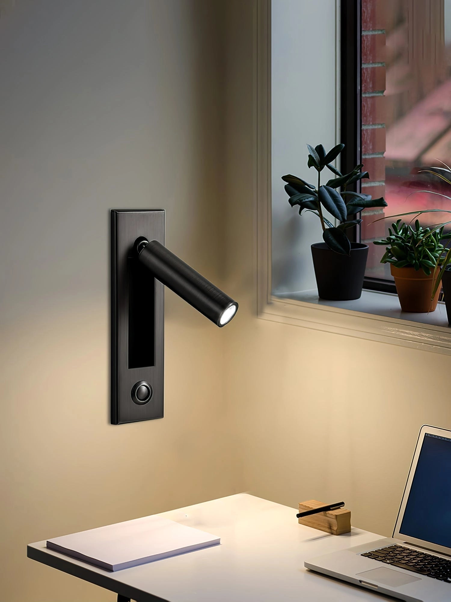 Modern adjustable black LED wall light with motion sensor mounted on a wall, illuminating a modern interior space with plants and a wooden table.