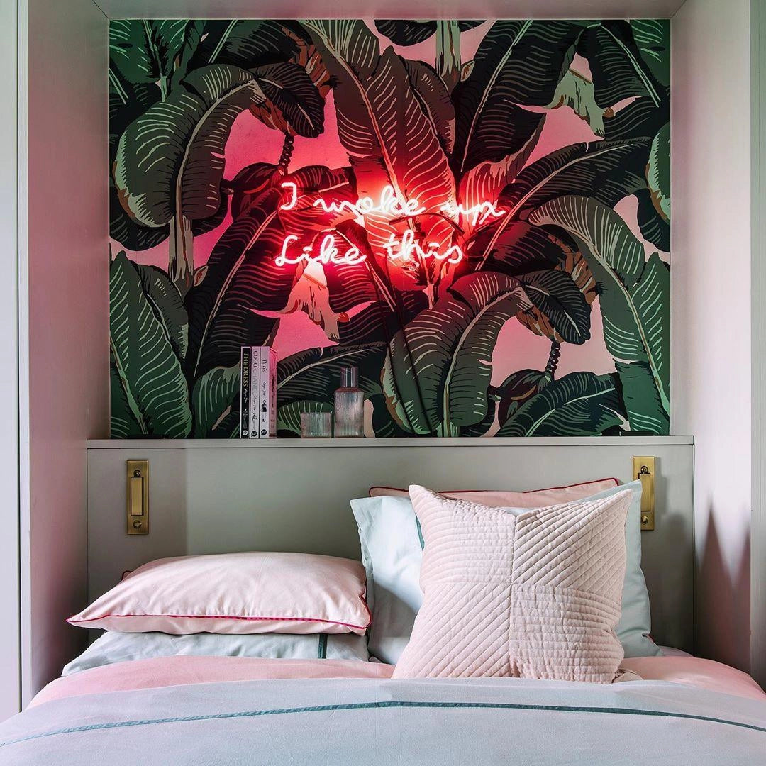 Modern adjustable black LED wall light with weather-resistant design and motion sensor, mounted on an interior wall, surrounded by contemporary decor including a framed picture, green plants, and comfortable furniture.