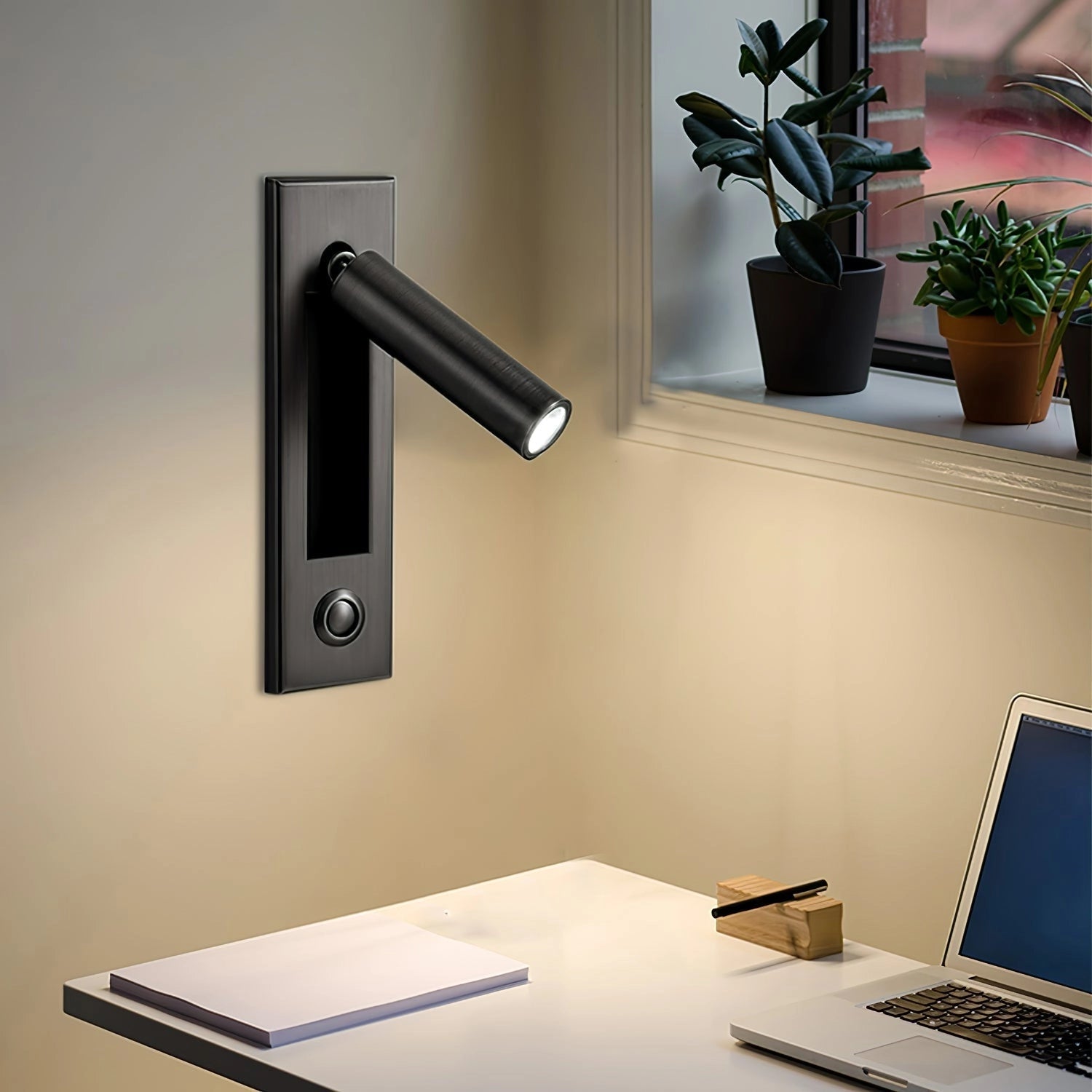 Black weather-resistant modern adjustable LED wall light with motion sensor mounted on an exterior wall near a small table with a flowerpot in an outdoor setting.