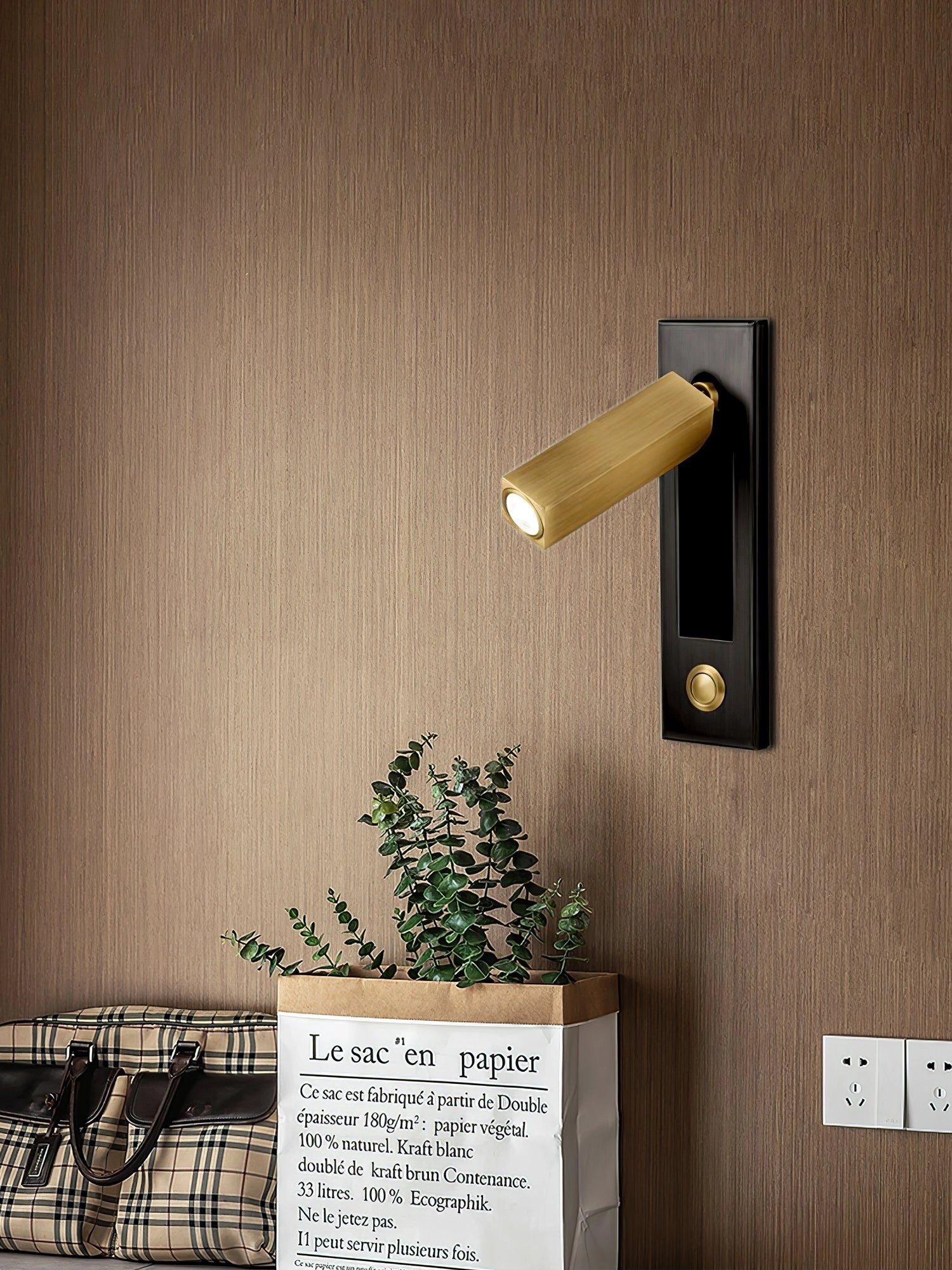 Modern adjustable black LED wall light with motion sensor mounted on a wooden wall, next to a plant.