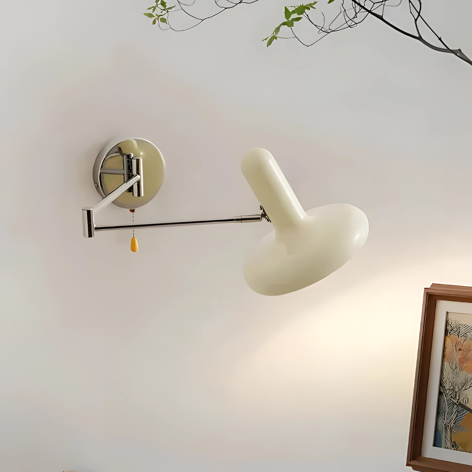 Modern adjustable reading light with a minimalist white sconce and chrome finish, mounted on a wall near a framed picture.