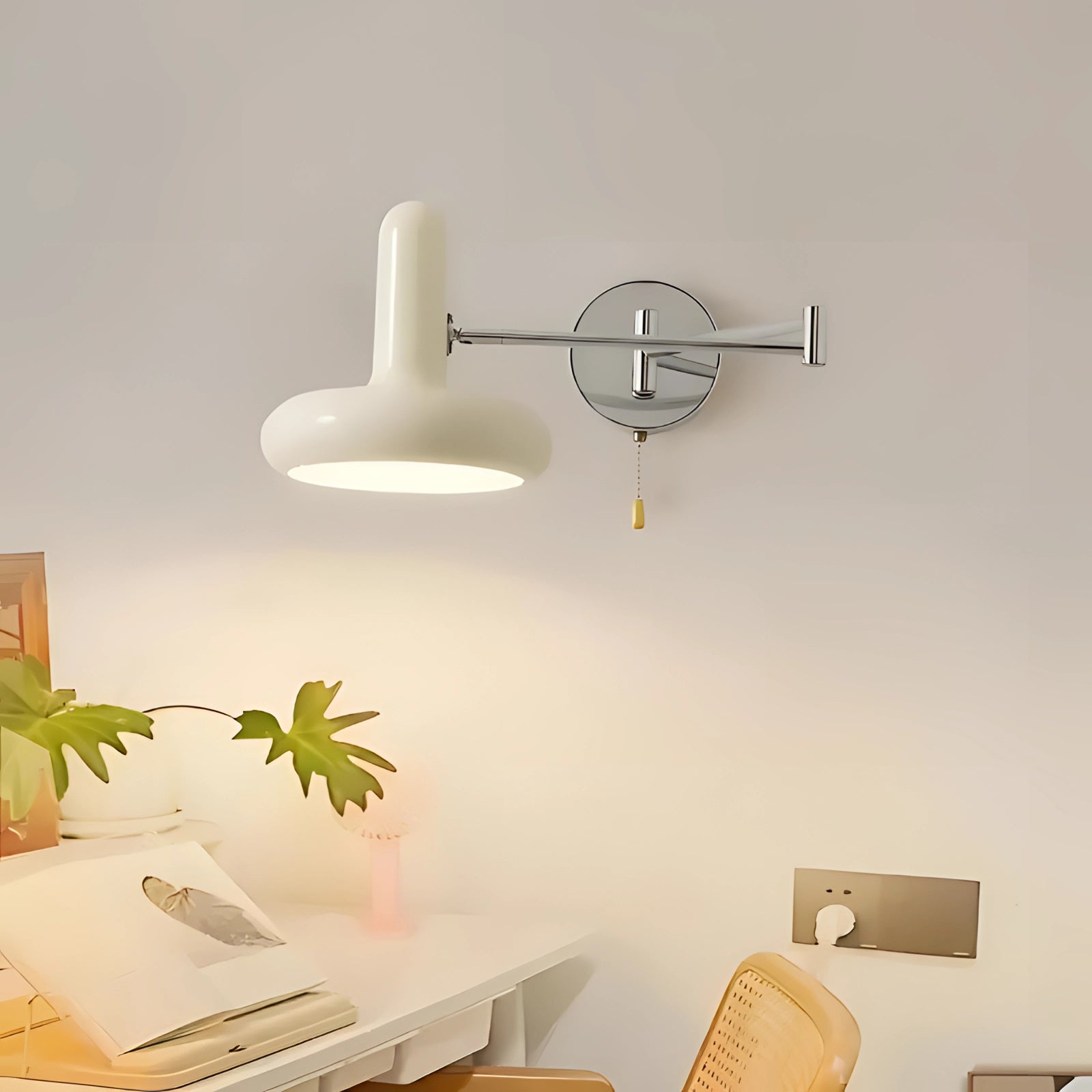 Modern minimalist white sconce with chrome finish mounted on a wall, providing adjustable lighting above a wooden table with shelving, surrounded by indoor plants, enhancing the comfort and interior design of the room.