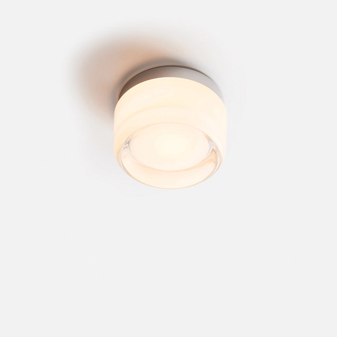 Amber glass pendant light with a modern design, featuring a white variant, suspended from a wooden ceiling fixture, casting a warm glow ideal for elegant dining room decor.