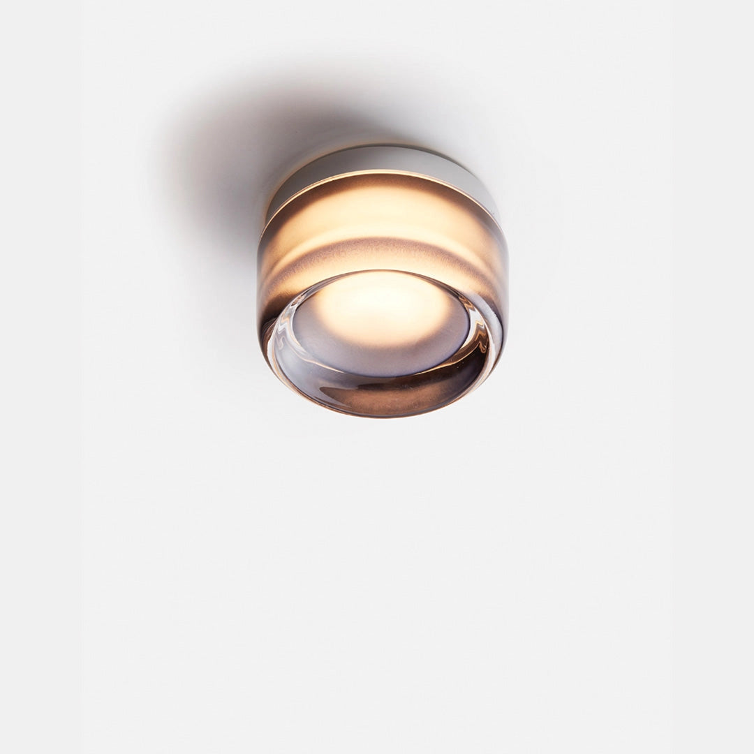 Modern amber glass pendant light with a gray finish, featuring a sleek circular design. The light is suspended from a metal ceiling mount, blending contemporary elegance with a warm, inviting glow, ideal for dining room decor.