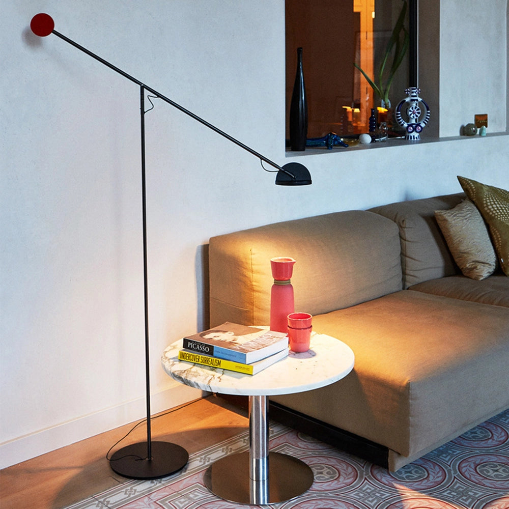 Sleek black modern arc floor lamp positioned in a stylish interior setting with a couch, highlighting its adjustable design and contributing to the contemporary architectural aesthetic.