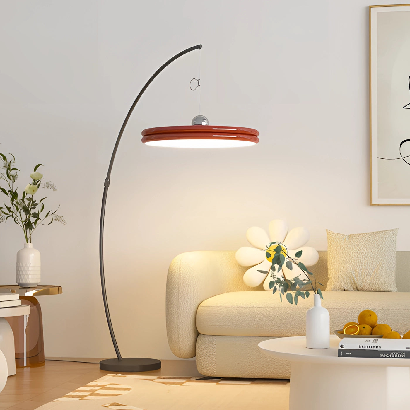 A modern arched floor lamp with a curved metallic finish and a large red shade, positioned in a stylish living room. The room features comfortable seating with a couch and a studio couch, complemented by houseplants and contemporary interior design elements, enhancing the cozy ambiance with its elegant lighting.