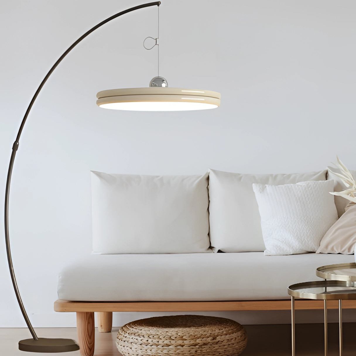Modern arched floor lamp with a curved metallic finish and large yellow shade, set against a neutral-toned interior with wooden and grey elements.