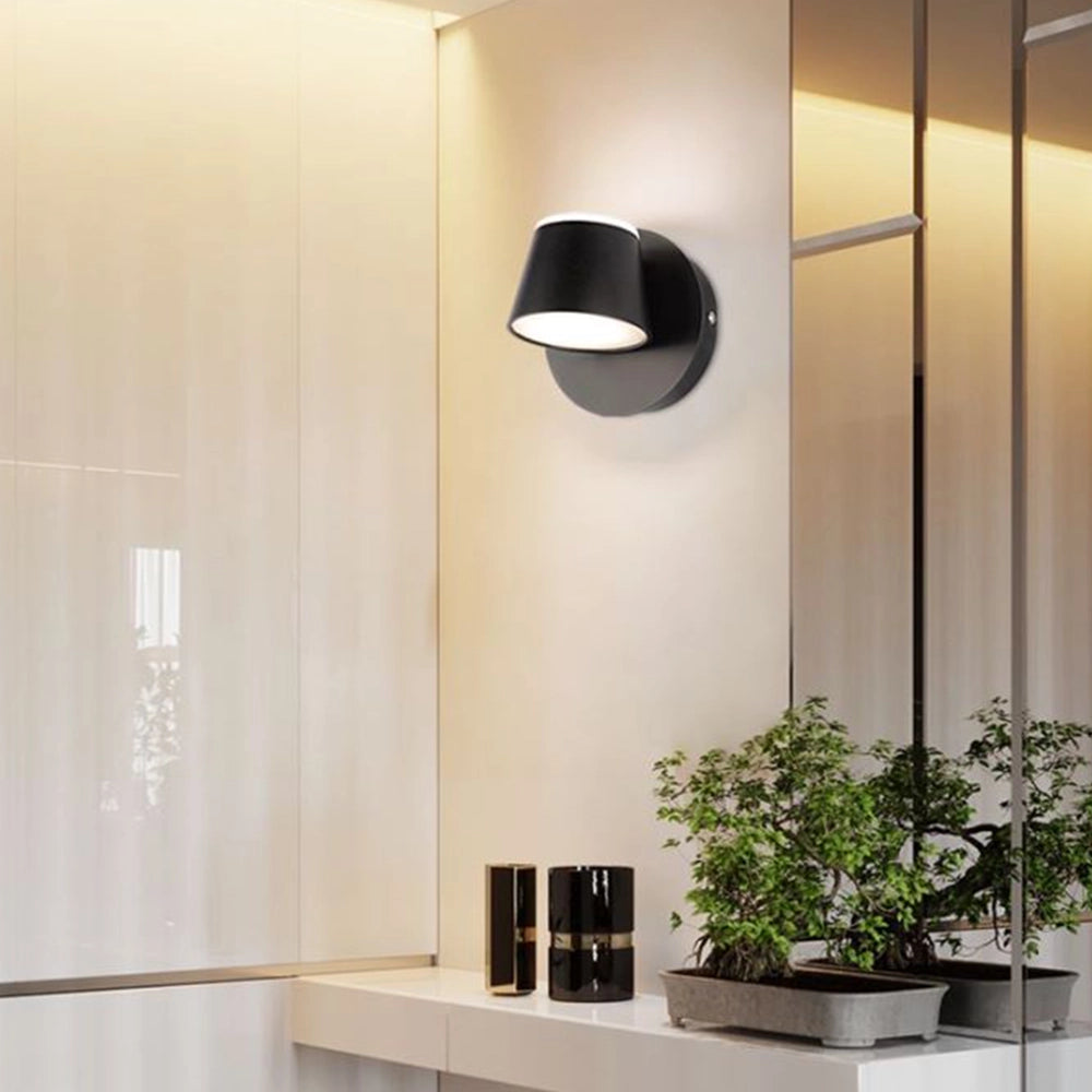 Modern black adjustable 4-light LED track light with a cool white bulb, mounted on a wooden wall in a stylish interior featuring plant decor and a wooden floor.