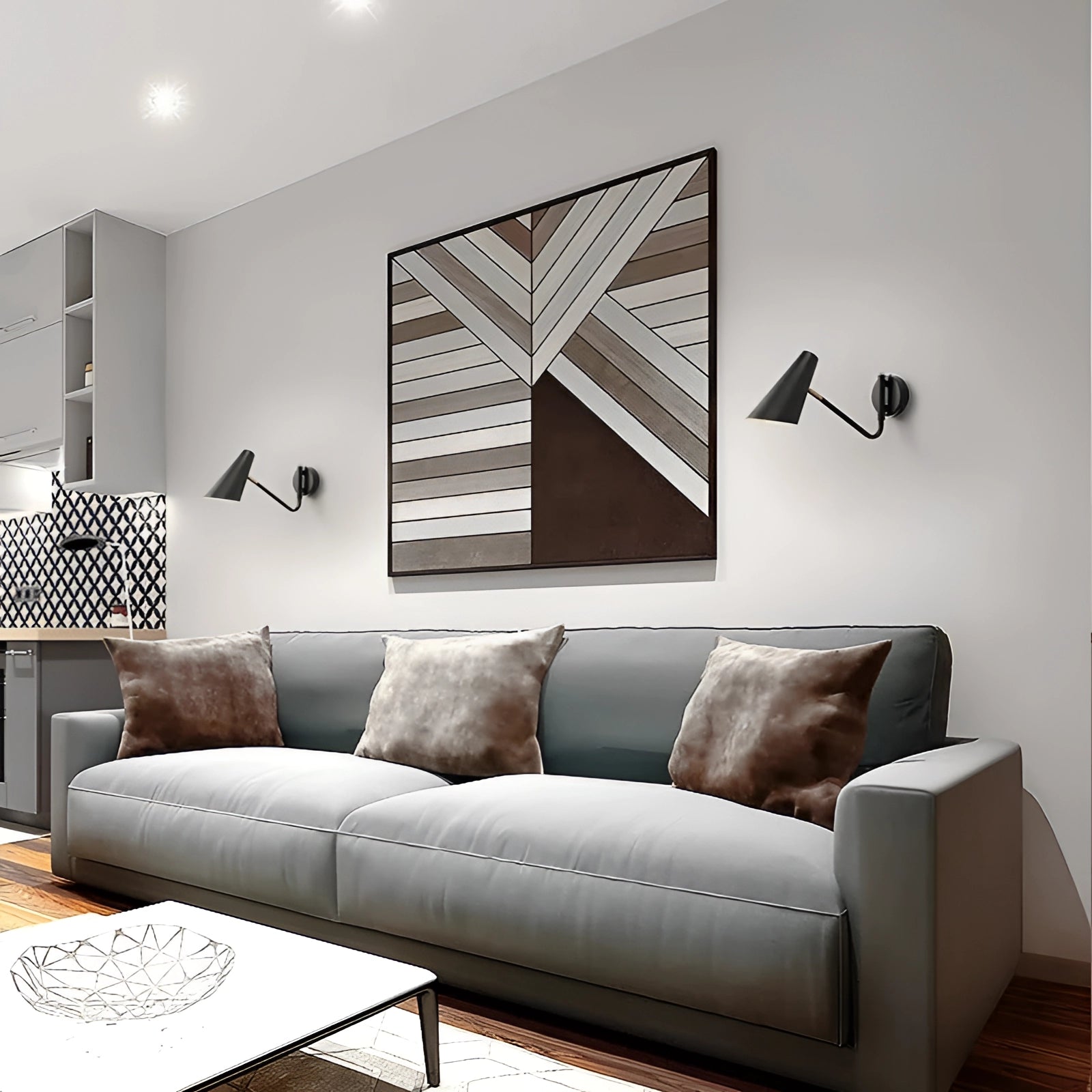 Modern black adjustable wall sconce with a minimalist industrial design mounted on a white wall near a wooden picture frame and a comfortable black couch.