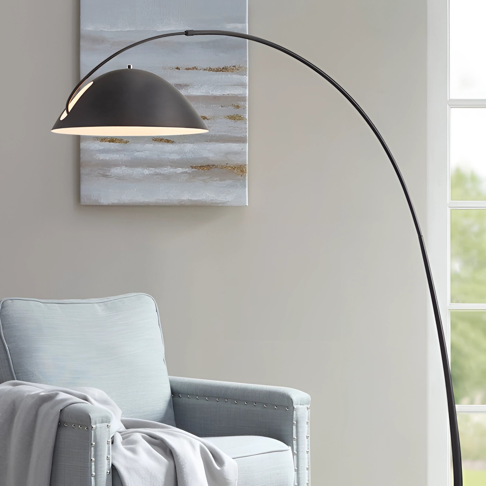 Modern black arched floor lamp with an adjustable dome shade, placed in a contemporary interior setting with grey tones and wooden elements.