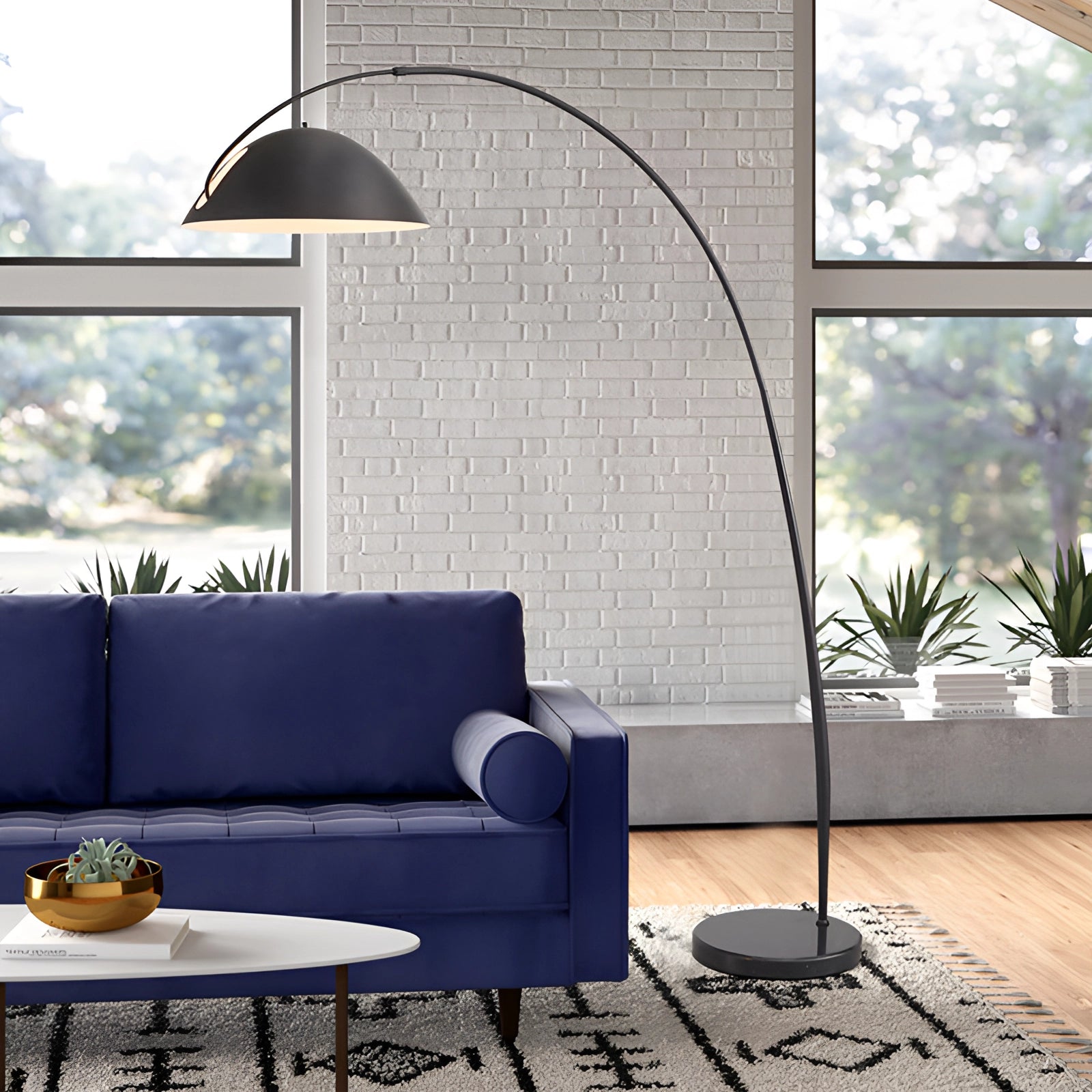 Modern black arched floor lamp with an adjustable dome shade, positioned in a stylish interior setting with a couch and indoor plant.