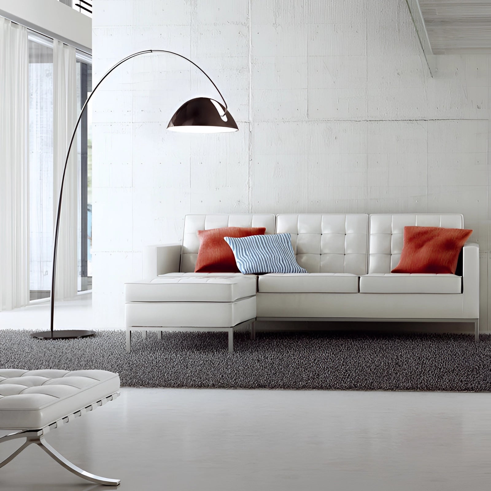 Modern black arched floor lamp with an adjustable dome reading light positioned next to a couch in a well-designed interior living space featuring wooden flooring.
