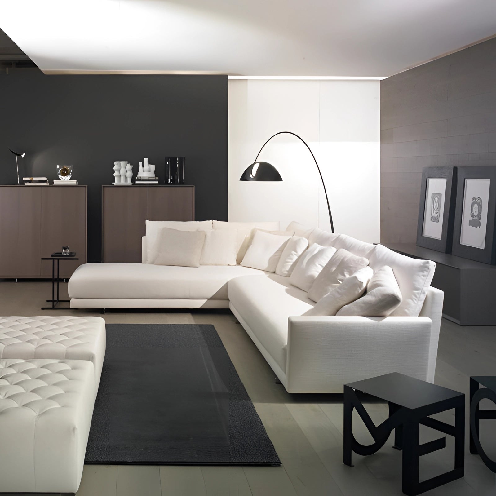 Modern black arched floor lamp with an adjustable dome shade, situated in a stylish living room setting featuring a grey studio couch and framed art on the wall.