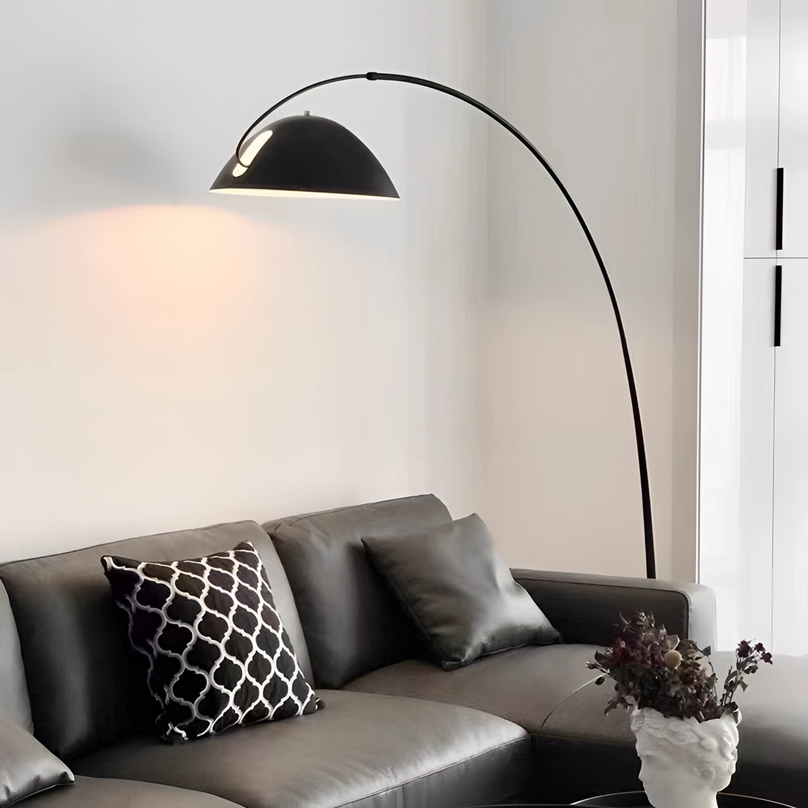 Modern black arched floor lamp with adjustable dome reading light in a cozy interior setting, featuring a comfortable couch, white walls, and a green plant.