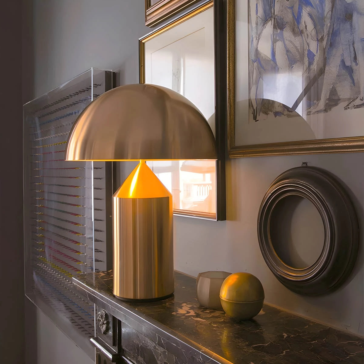 Modern black and gold dome pendant light hanging over a wooden desk, illuminating a stylish interior space with luxury decor elements.
