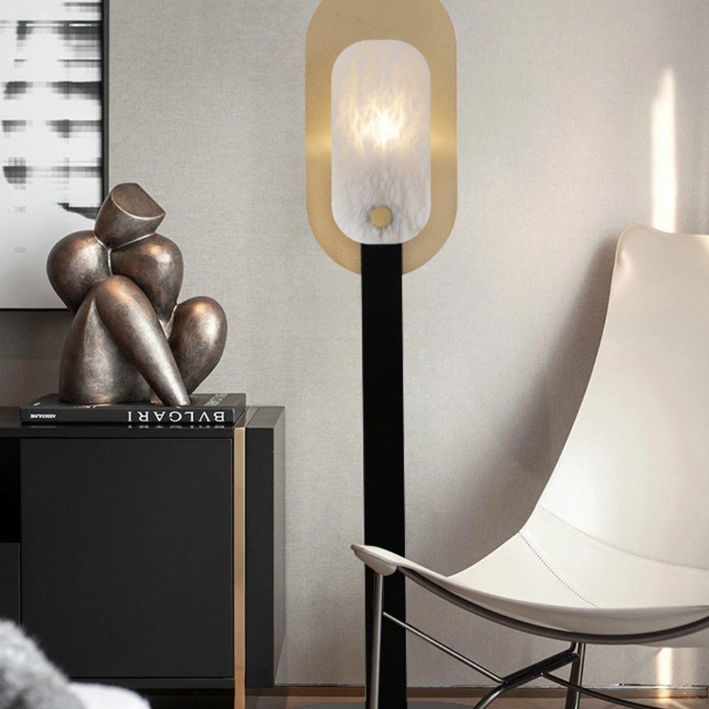 Modern black and gold LED floor lamp with a minimalist oval shade design, emitting a warm light, positioned in a stylish interior setting.