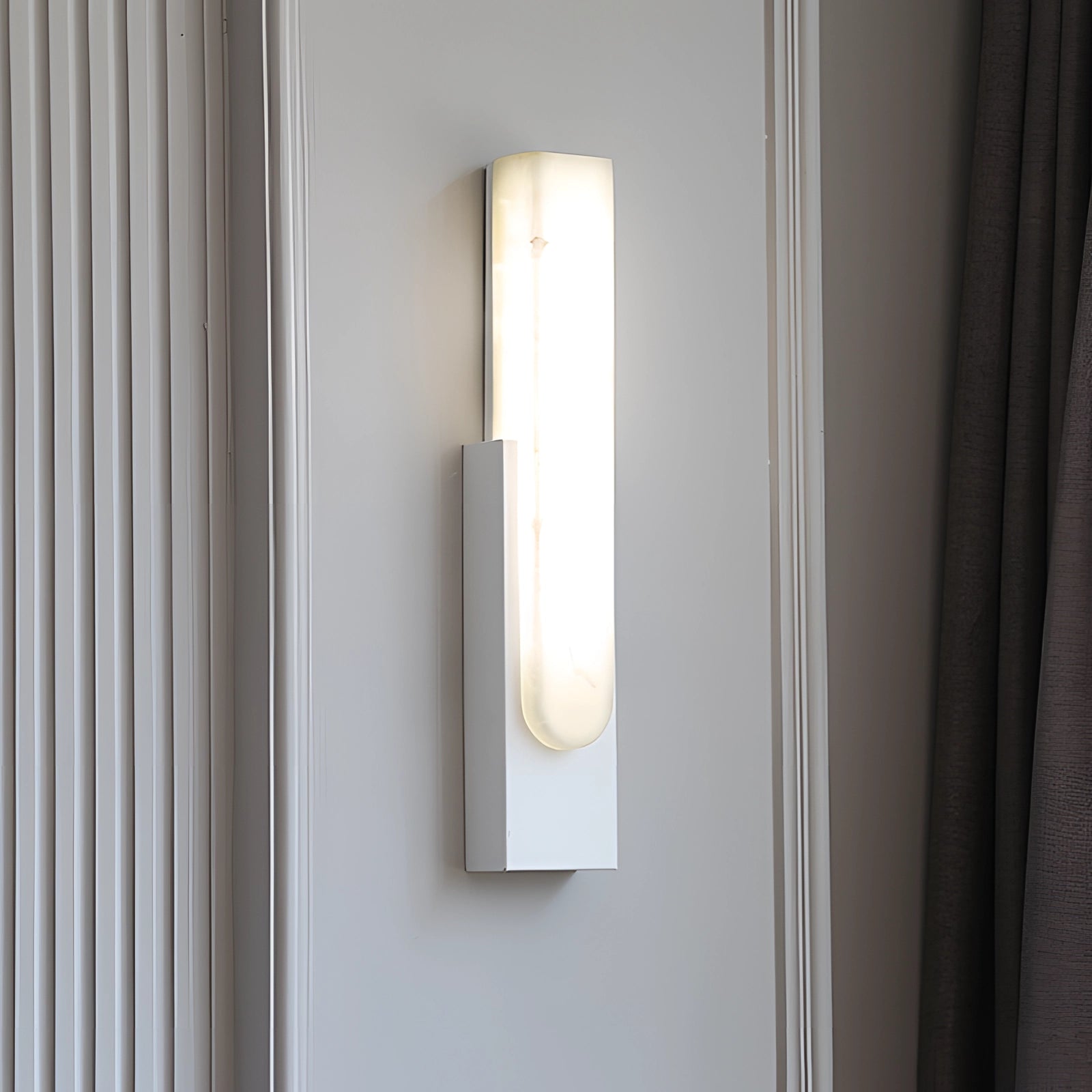 Modern black and gold LED wall sconce with a minimalist design, mounted on a white wall, featuring a sleek rectangular shape and glass accents.