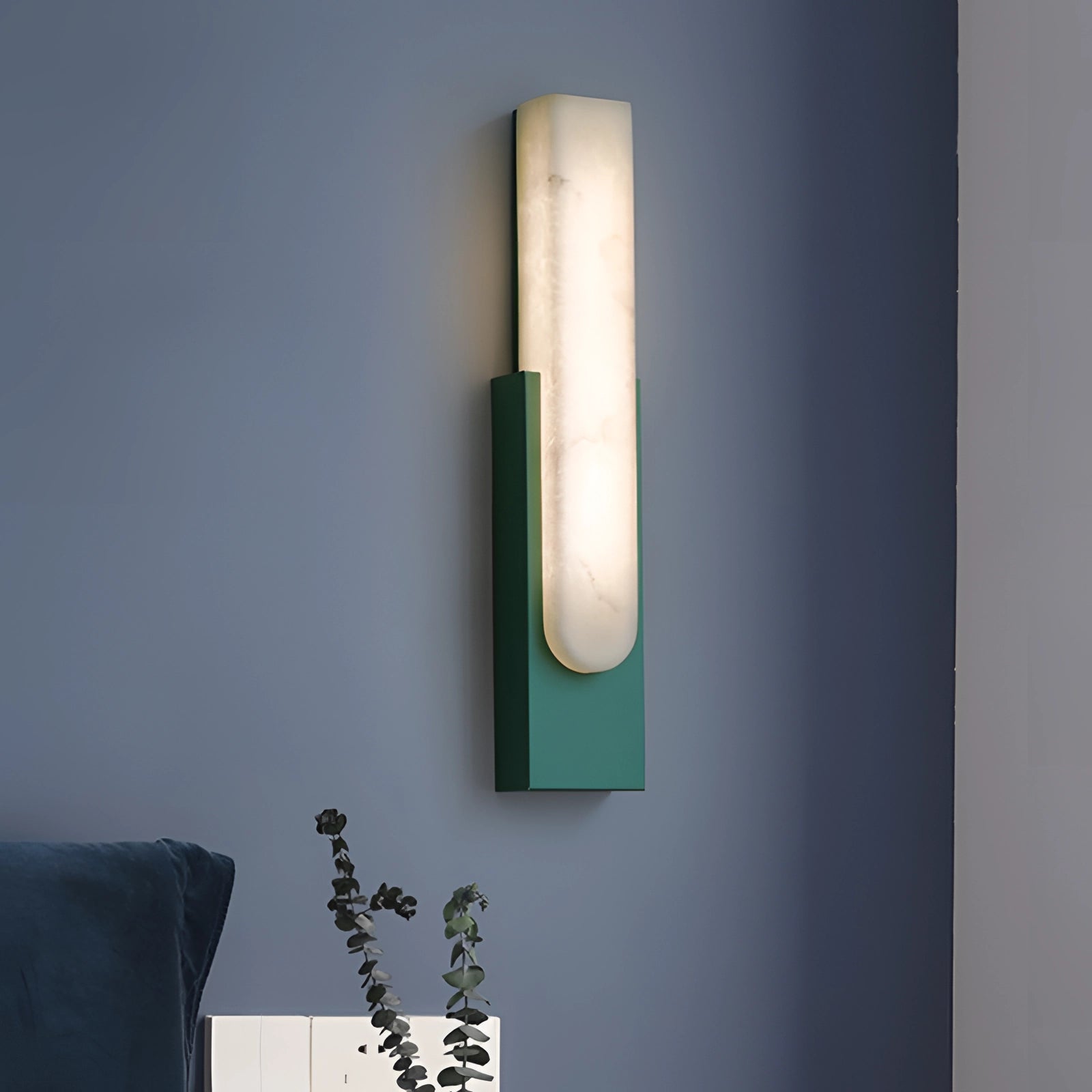 Modern black and gold LED wall sconce with a minimalist design, featuring a rectangular form and warm light, mounted on an indoor wall near a green couch.