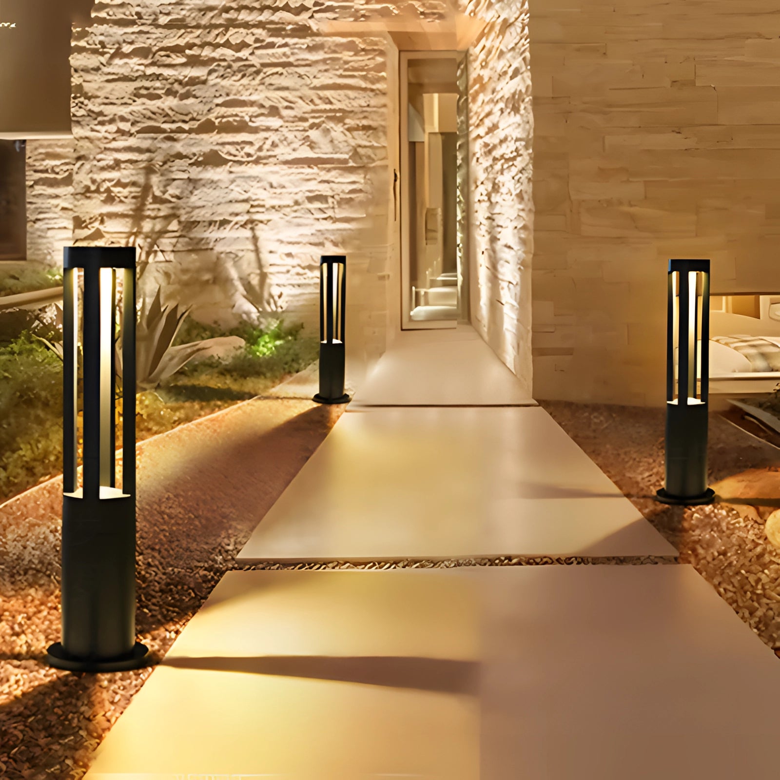 Modern black LED cylinder lamp, 40cm tall, placed outdoors near wooden flooring and surrounded by plants, emitting warm yellow light, showcasing its waterproof design.