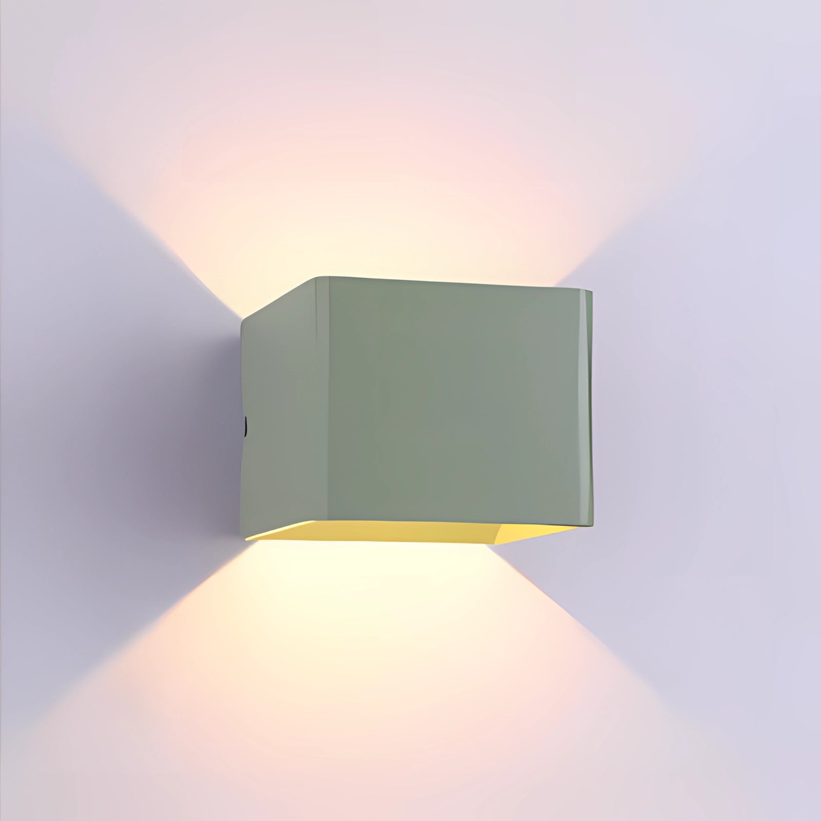 Modern black LED wall sconce with a geometric design, mounted on a wall. The setting features a green variant of the light fixture, contrasting against a neutral-toned background.