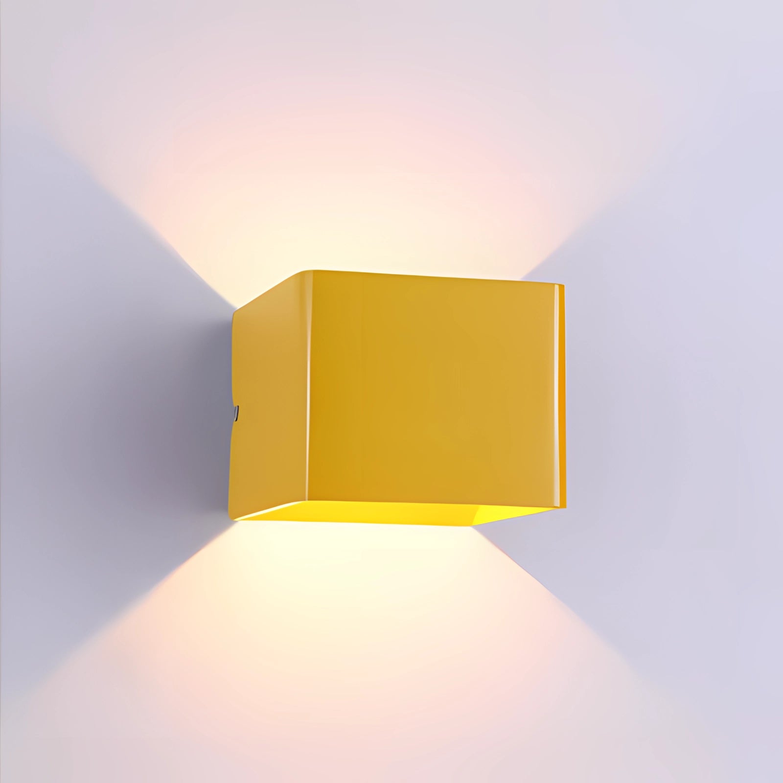 Modern black LED wall sconce with a geometric design, featuring a yellow tint that casts an amber glow. The fixture is mounted on an exterior wall, showcasing a sleek rectangular shape with a metal finish.